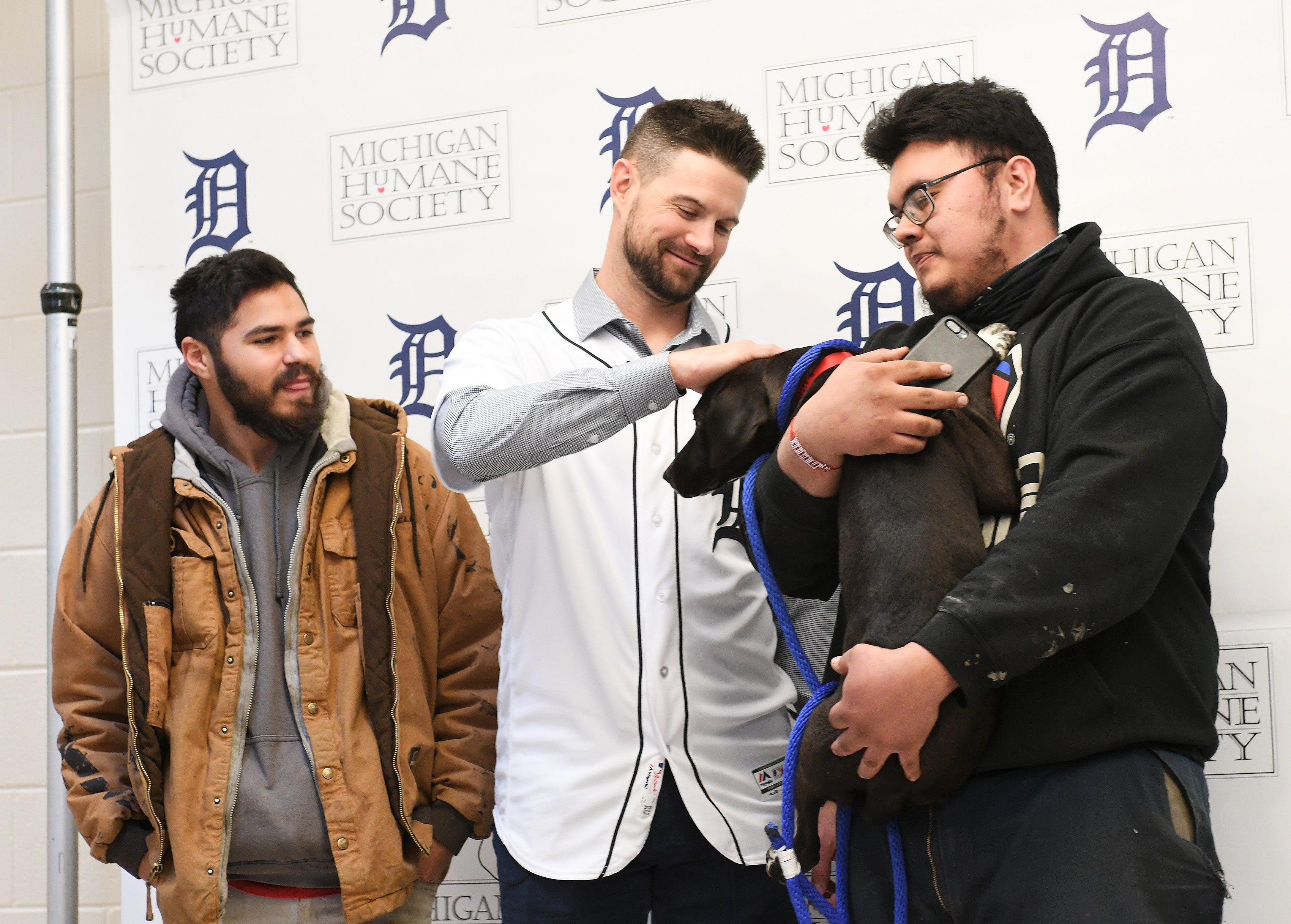 Tigers shortstop Jordy Mercer pets Lark who is being adopted by Marcelo Alvarado, 24, of Detroit, right, 25, with Marcelo's cousin, Gabriel Angel 25, left, at the Michigan Humane Society.