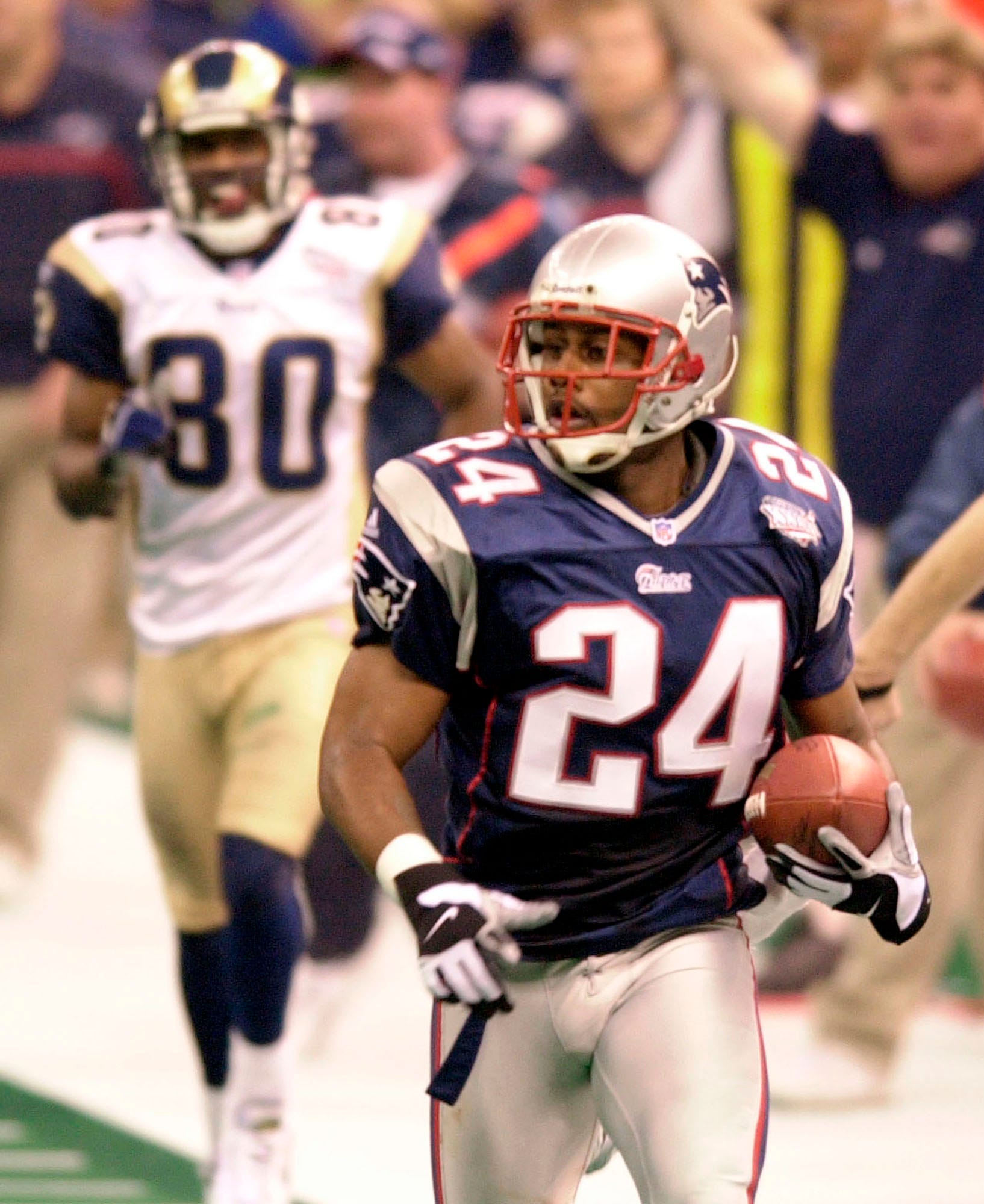 New England Patriots cornerback Ty Law (24) is trailed by St. Louis Rams' Isaac Bruce (80) as he scores a touchdown during the second quarter of Super Bowl XXXVI.