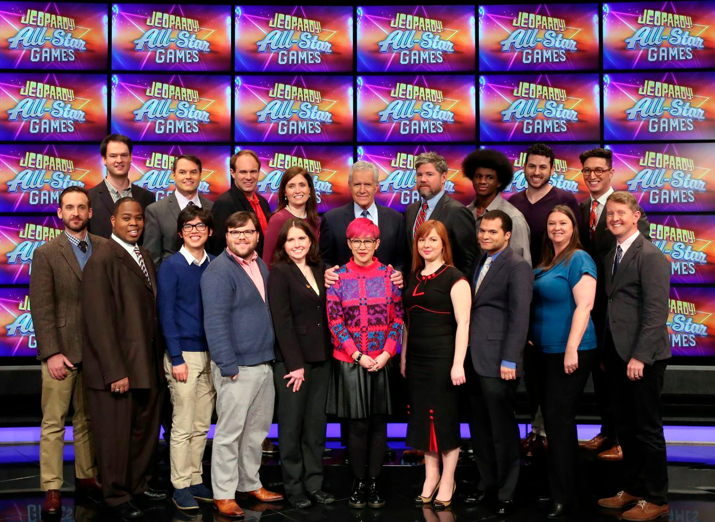 This image released by Jeopardy Productions, Inc. shows, front row from left, Brad Rutter, Colby Burnett, Alan Lin, Seth Wilson, Larissa Kelly, Monica Thieu, Pam Mueller, Matt Jackson, Jennifer Giles and Ken Jennings, back row from left, Ben Ingram,  Roger Craig, David Madden, Julia Collins, host Alex Trebek, Austin Rogers, Leonard Cooper, Alex Jacob and Buzzy Cohen on the set of the game show "Jeopardy!"