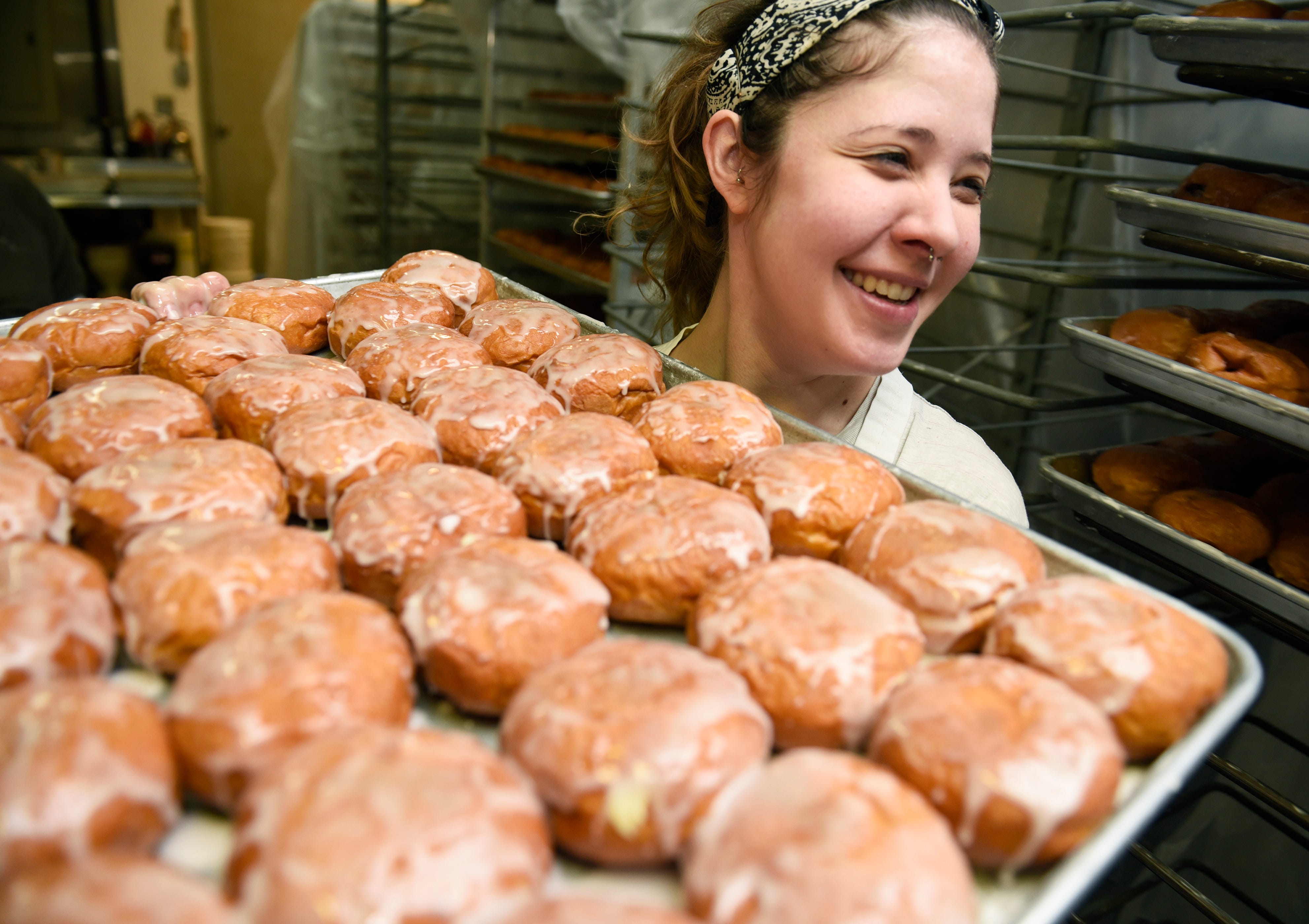 Petrisha Bakic, 28, carries a tray of paczki from the kitchen to the front counter for waiting customers at New Martha Washington Bakery.
