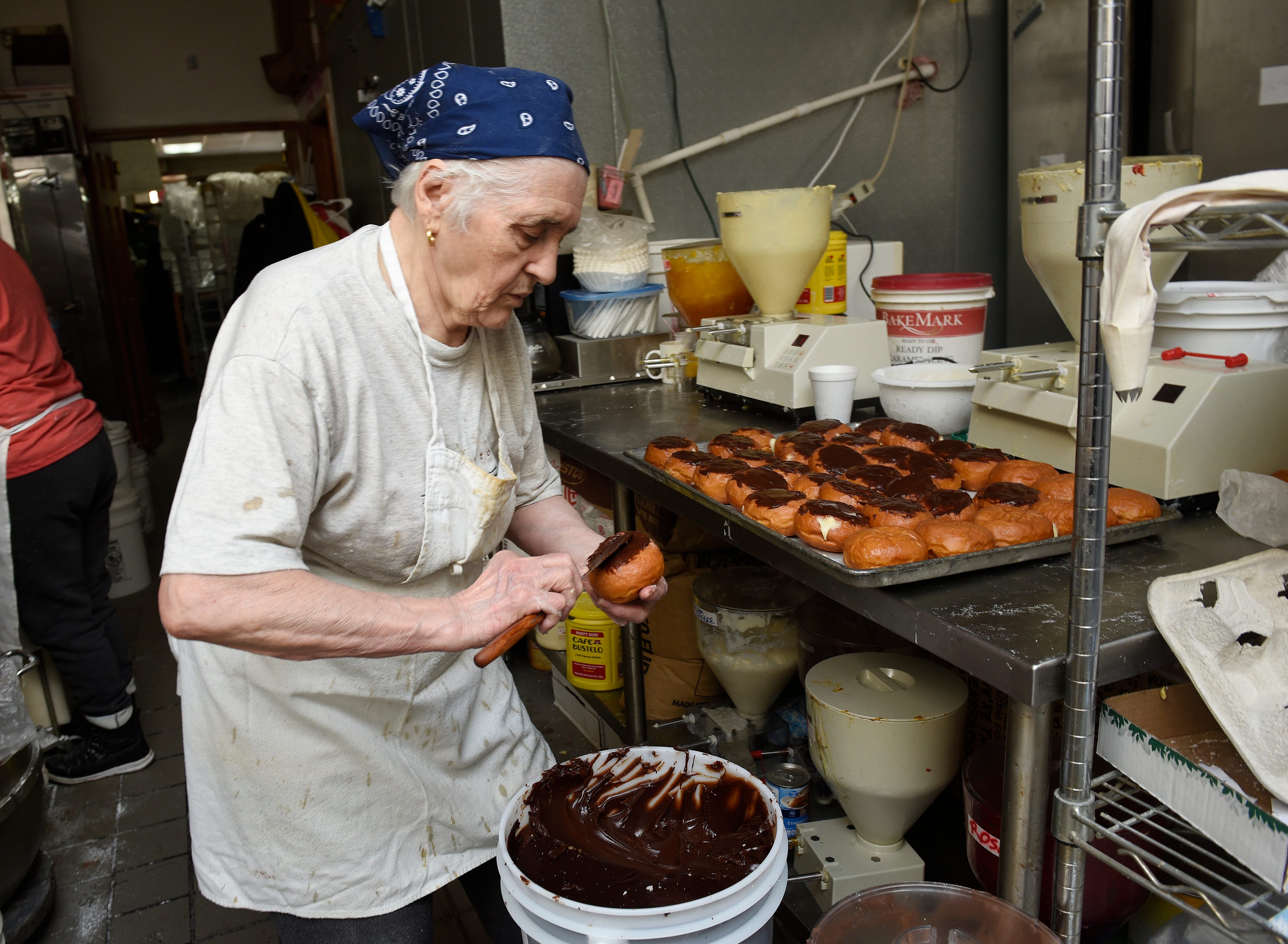 Ivanka Petrovic, co-owner of the bakery applies chocolate fudge on a Boston Cream paczek.