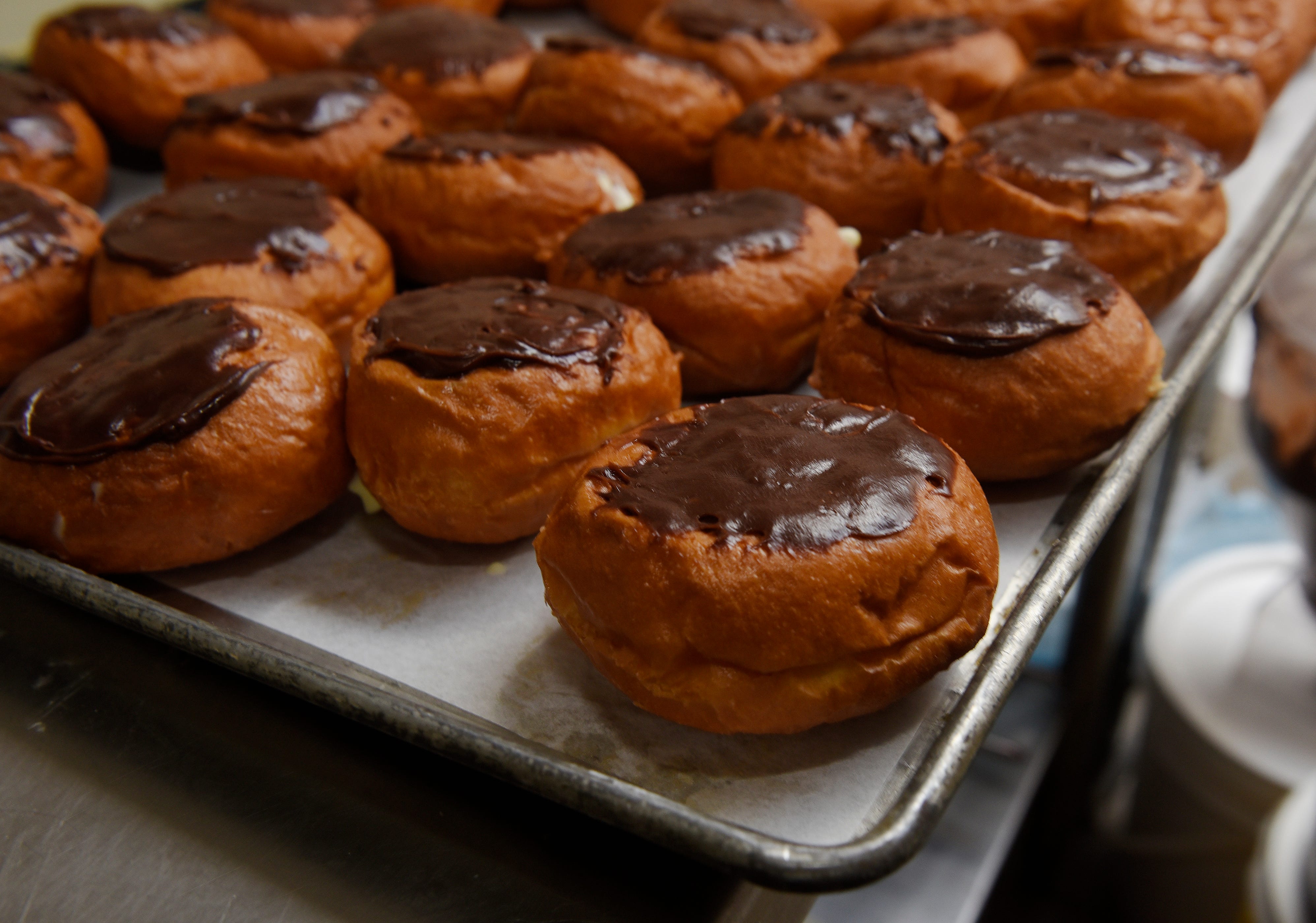 A tray of Boston Cream with chocolate fudge paczki are ready for purchase.