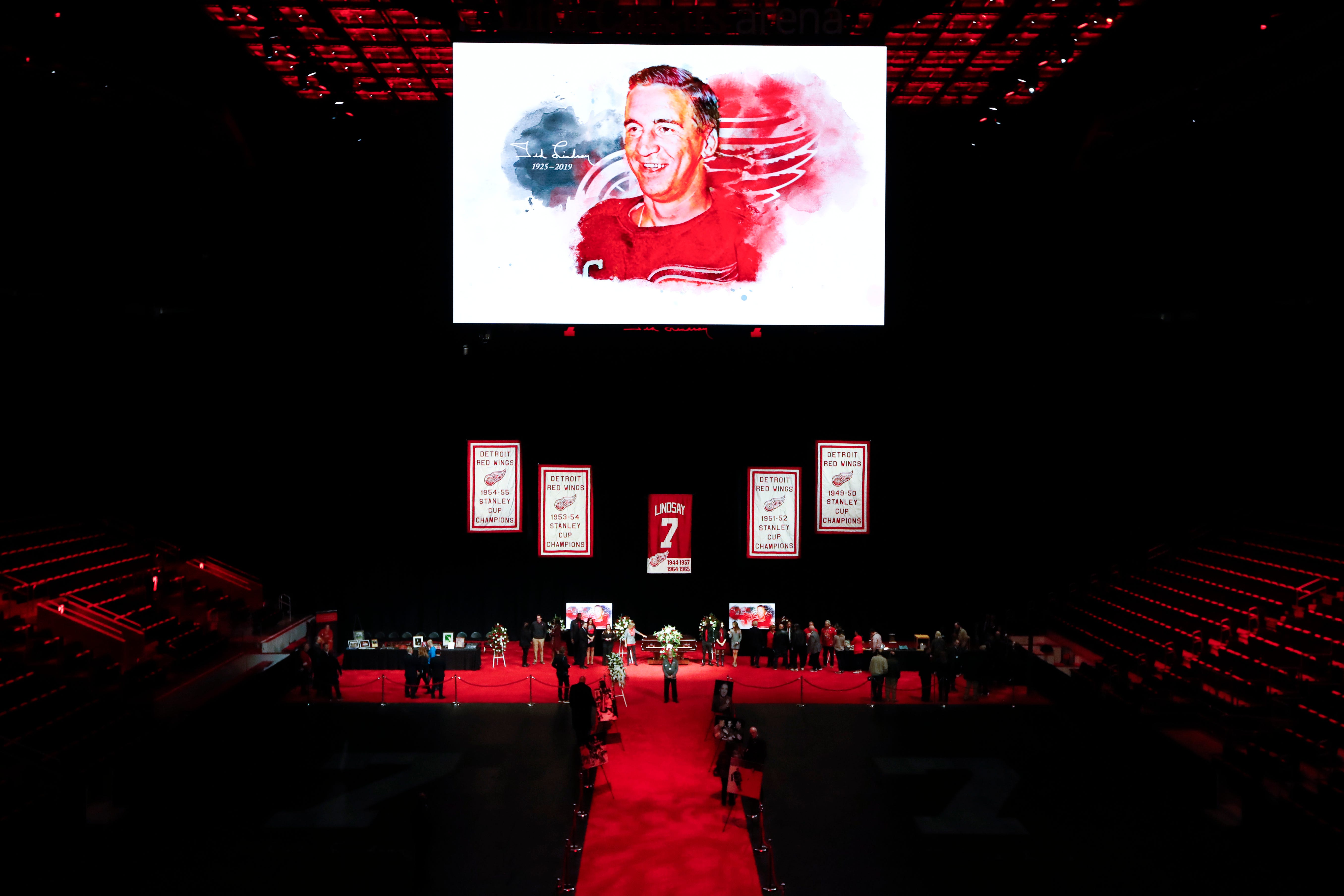 An illustration of Ted Lindsay is projected on the scoreboard as mourners view the casket in Little Caesars Arena.