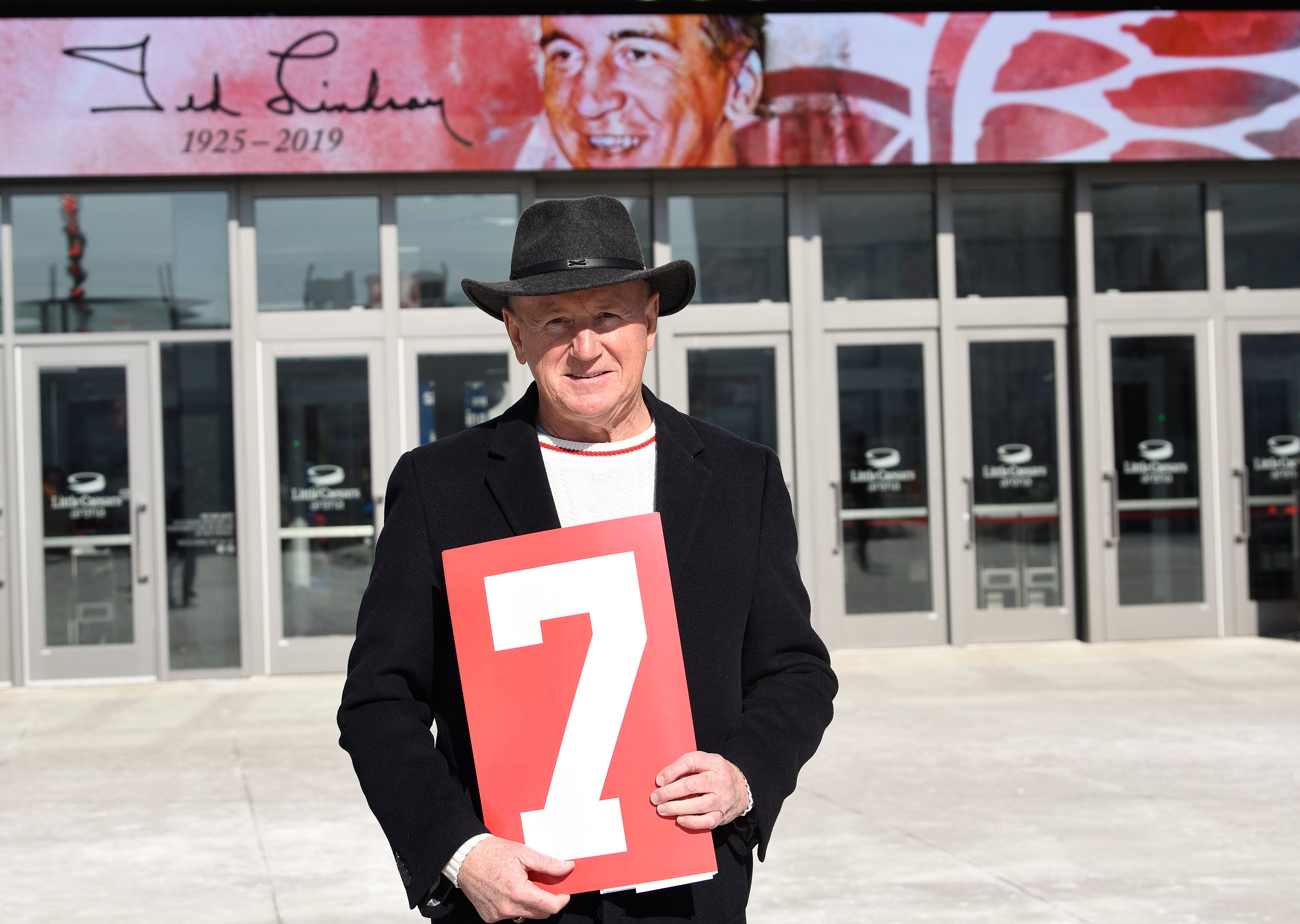 John Martin, 70, of Riverview stands in front of Little Caesars Arena holding a #7 placard in honor of Ted Lindsay.