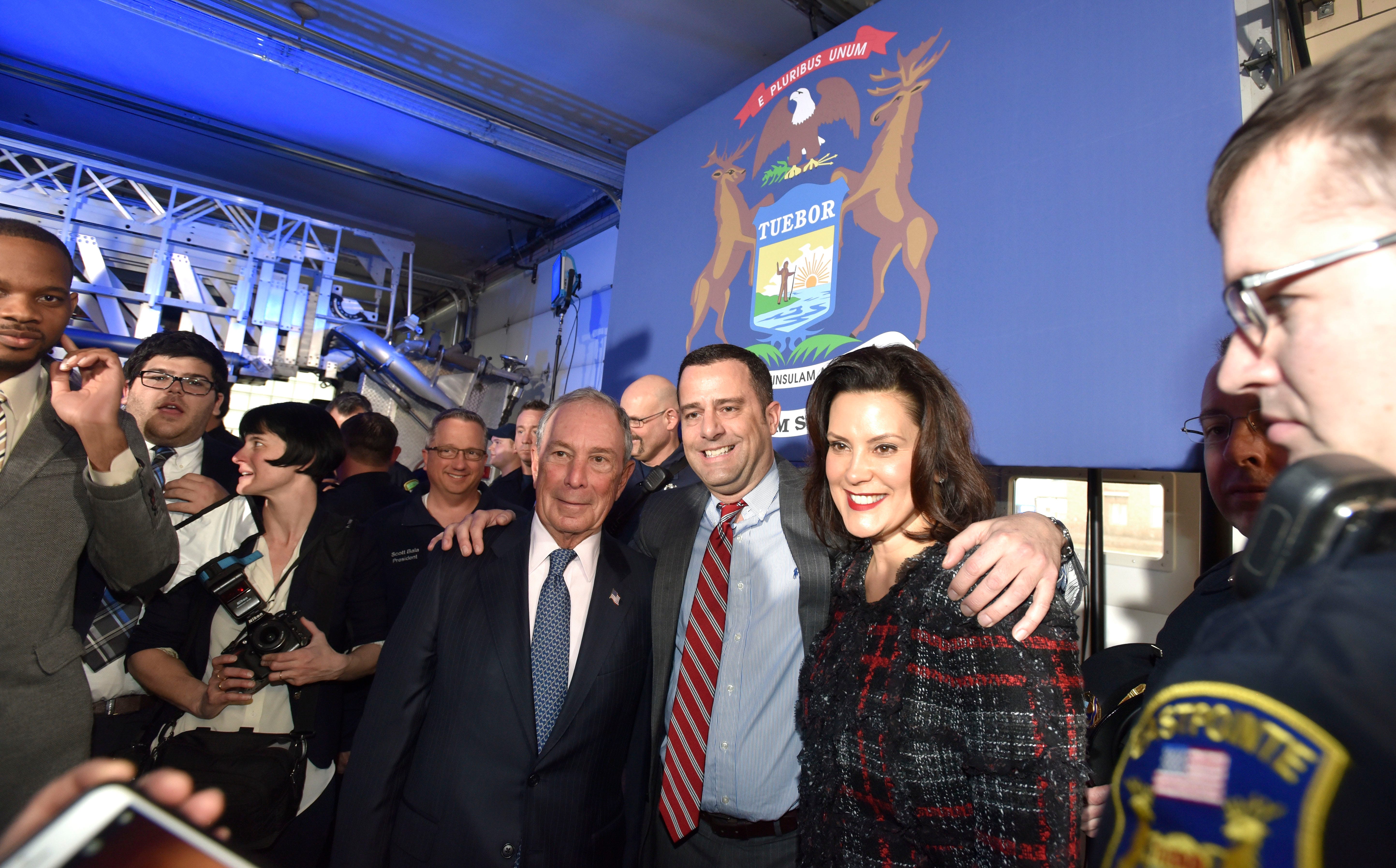 Former City of New York Mayor Michael Bloomberg, left, and Michigan Governor Gretchen Whitmer, right, take pictures with attendees after the press conference.