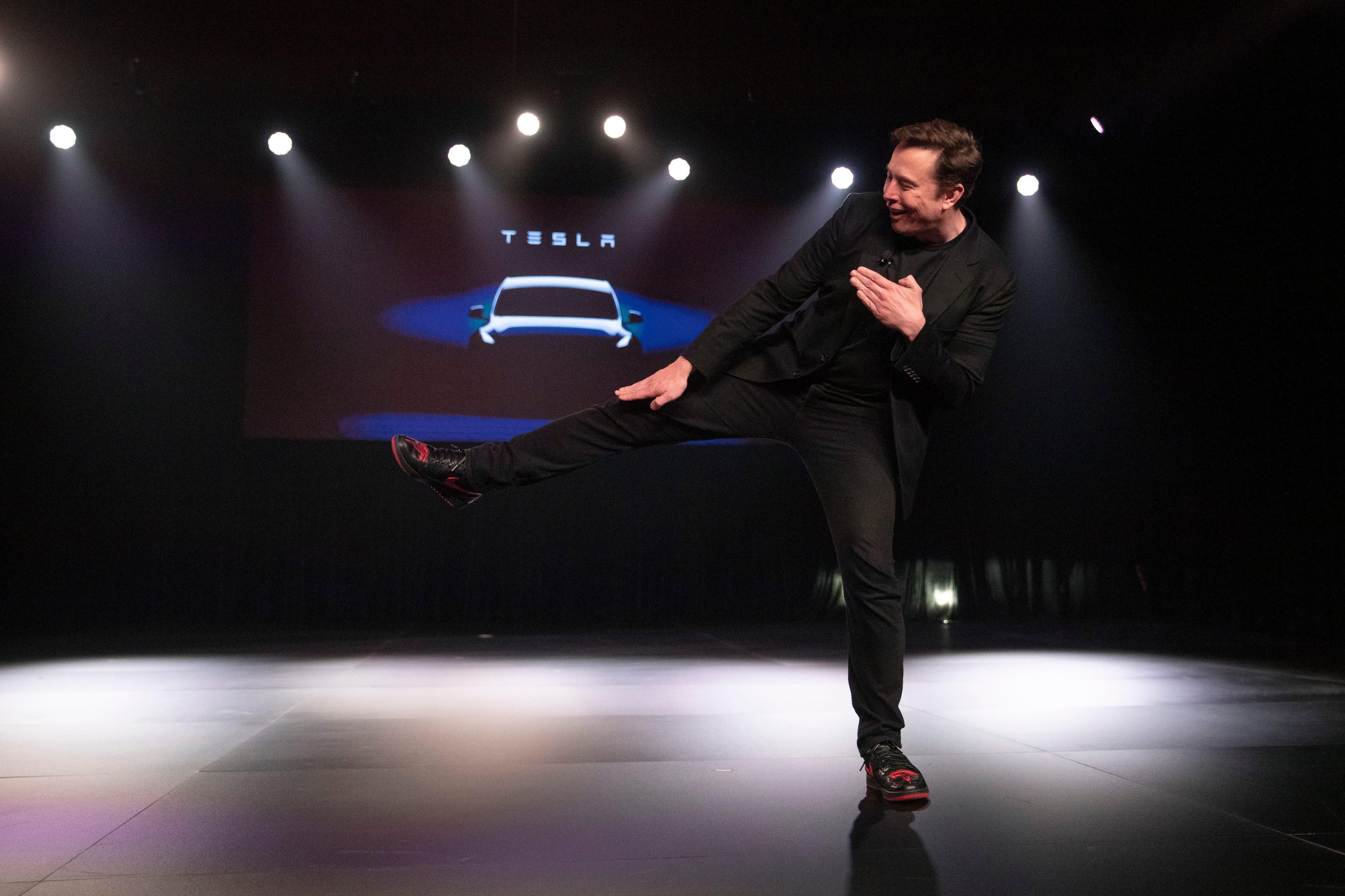 Tesla CEO Elon Musk jokingly kicks before introducing the Model Y at Tesla's design studio Thursday, March 14, 2019, in Hawthorne, Calif. The Model Y may be Tesla's most important product yet as it attempts to expand into the mainstream and generate enough cash to repay massive debts that threaten to topple the Palo Alto, Calif., company.