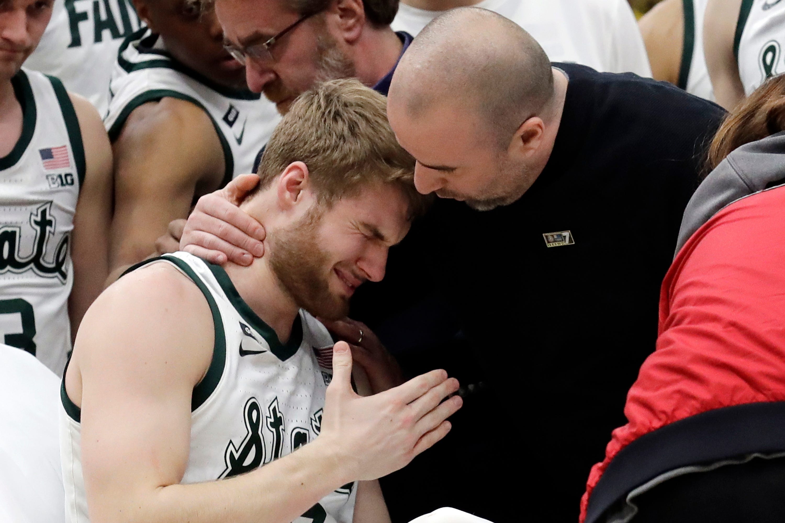 Medical personnel took talks to Michigan State's Kyle Ahrens, left, as Ahrens was the taken out of the court for injury during the first half of Sunday's Big Ten tournament title game.