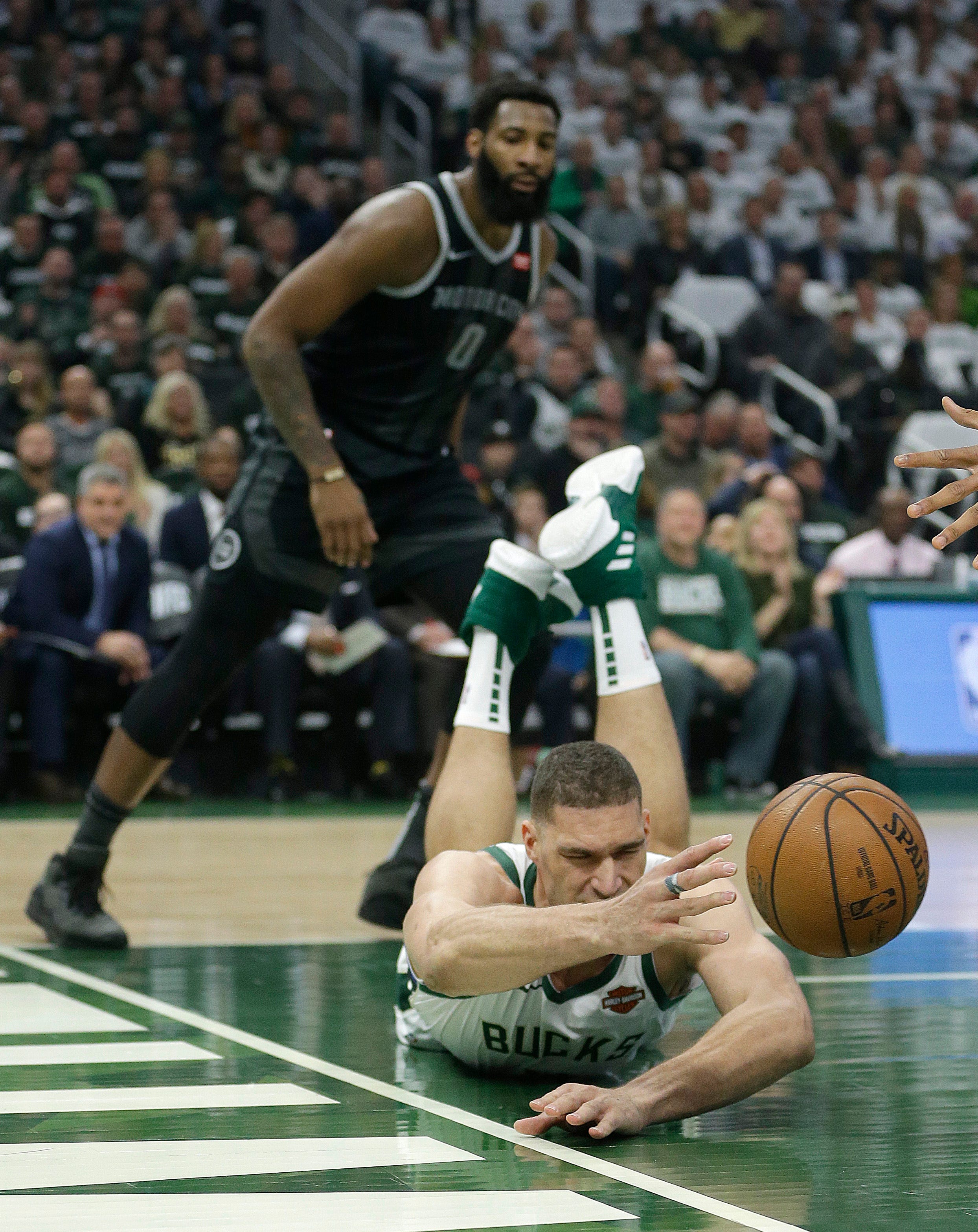 Bucks ' Brook Lopez is unable to save the ball from going out of bounds in front of Pistons ' Andre Drummond during the first half.