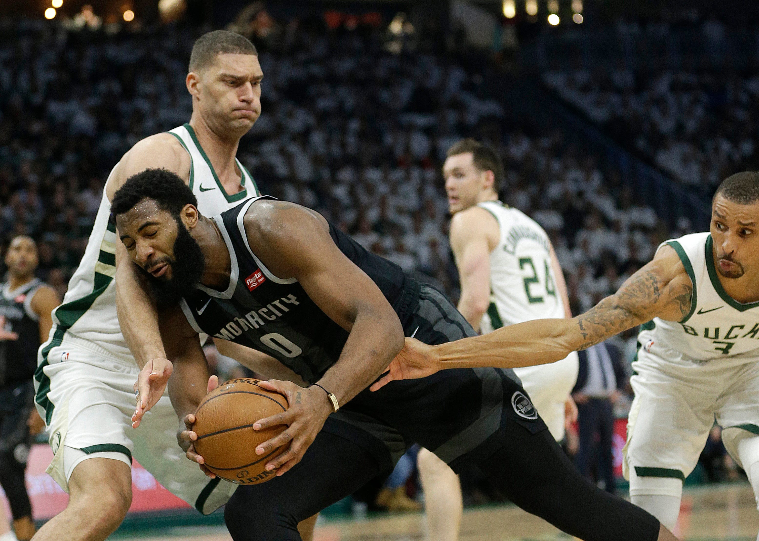 Pistons ' Andre Drummond (0) is fouled as he drives between Bucks ' Brook Lopez and George Hill during the first half.
