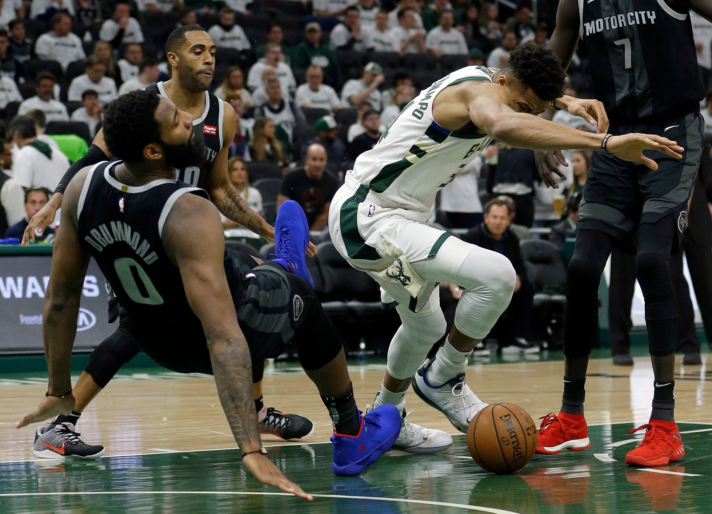Bucks ' Giannis Antetokounmpo commits an offensive foul against Pistons ' Andre Drummond during the second half.