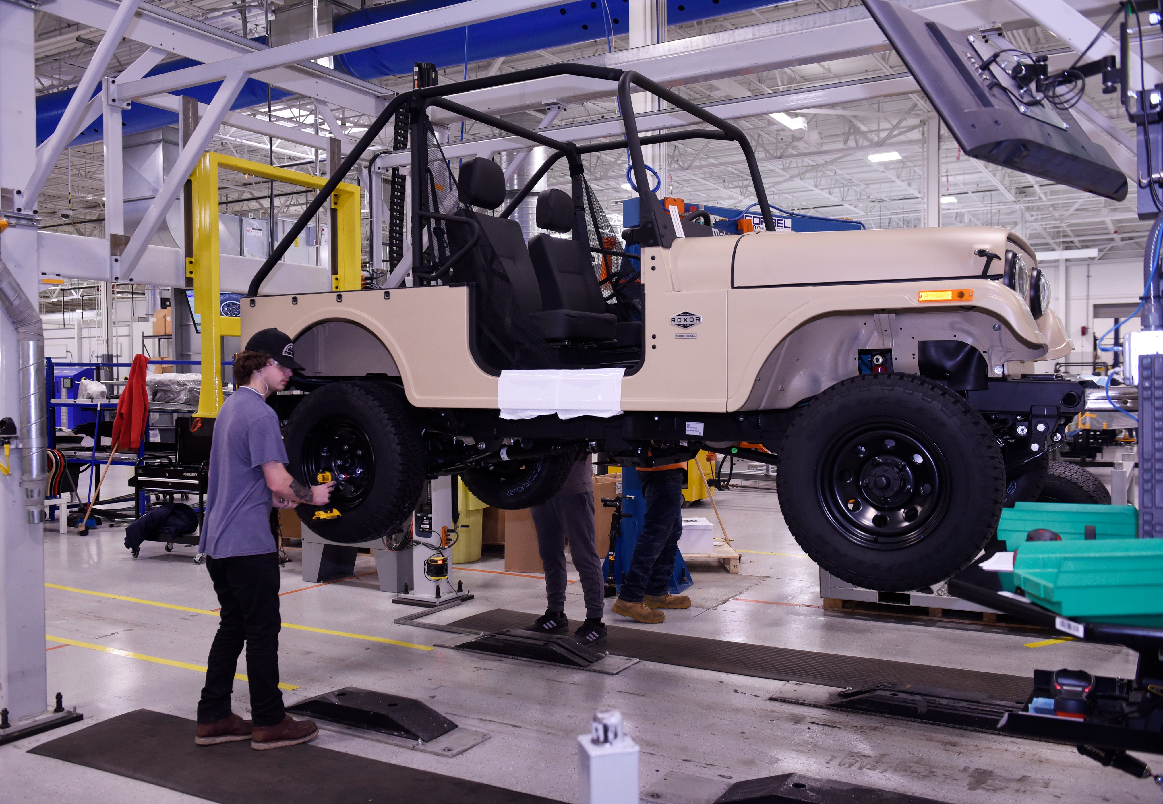 Jacob Myers installs wheels on a Mahindra Roxor off-road utility vehicle at Mahindra's Auburn Hills plant. The India-based vehicle maker and Ford Motor Co. will co-develop a midsize SUV for sale in India and emerging markets.