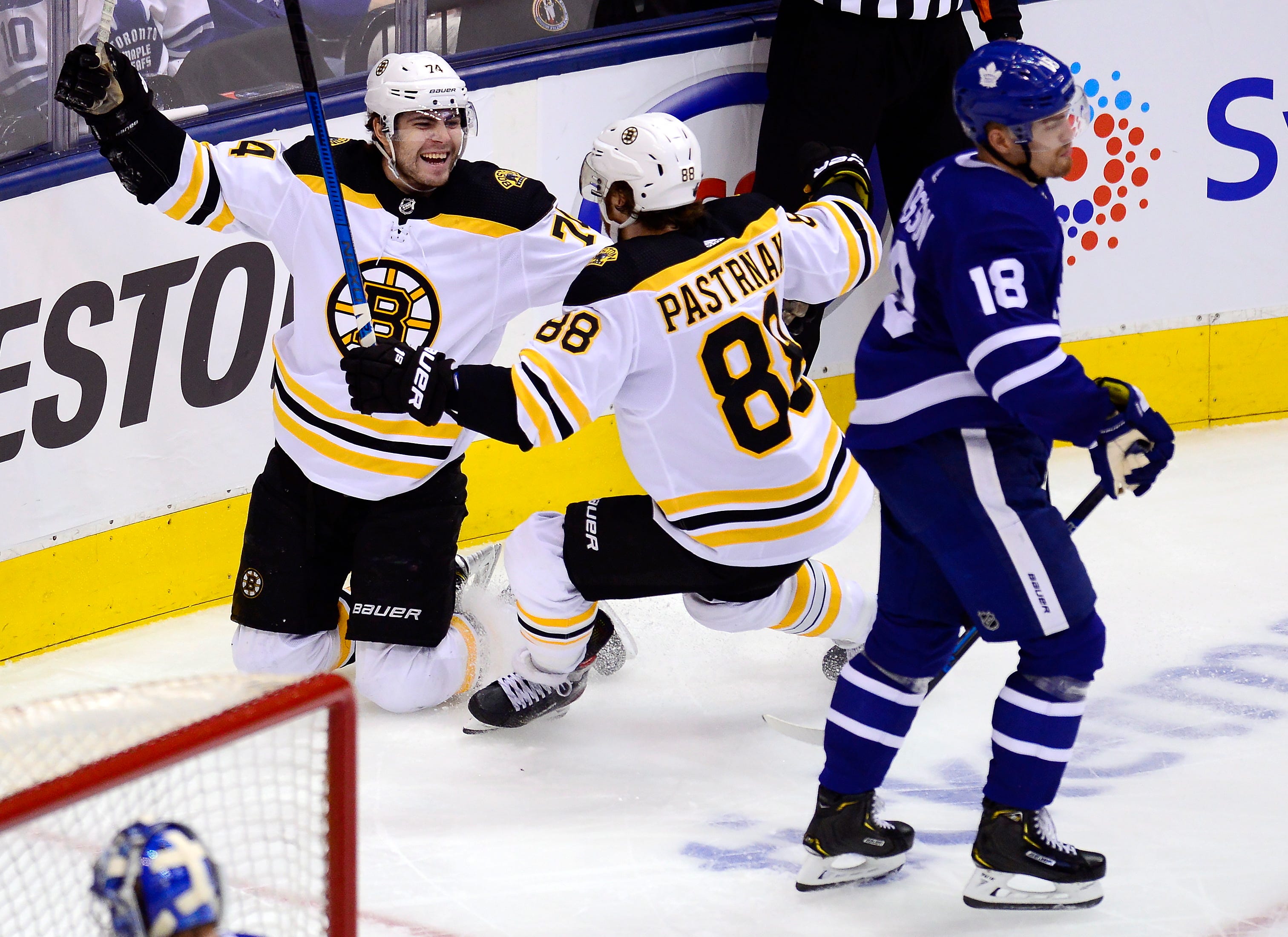 Bruins left wing Jake DeBrusk (74) celebrates his goal with right wing David Pastrnak (88) as Maple Leafs left wing Andreas Johnsson (18) skates by during the second period of Game 6 on Sunday.