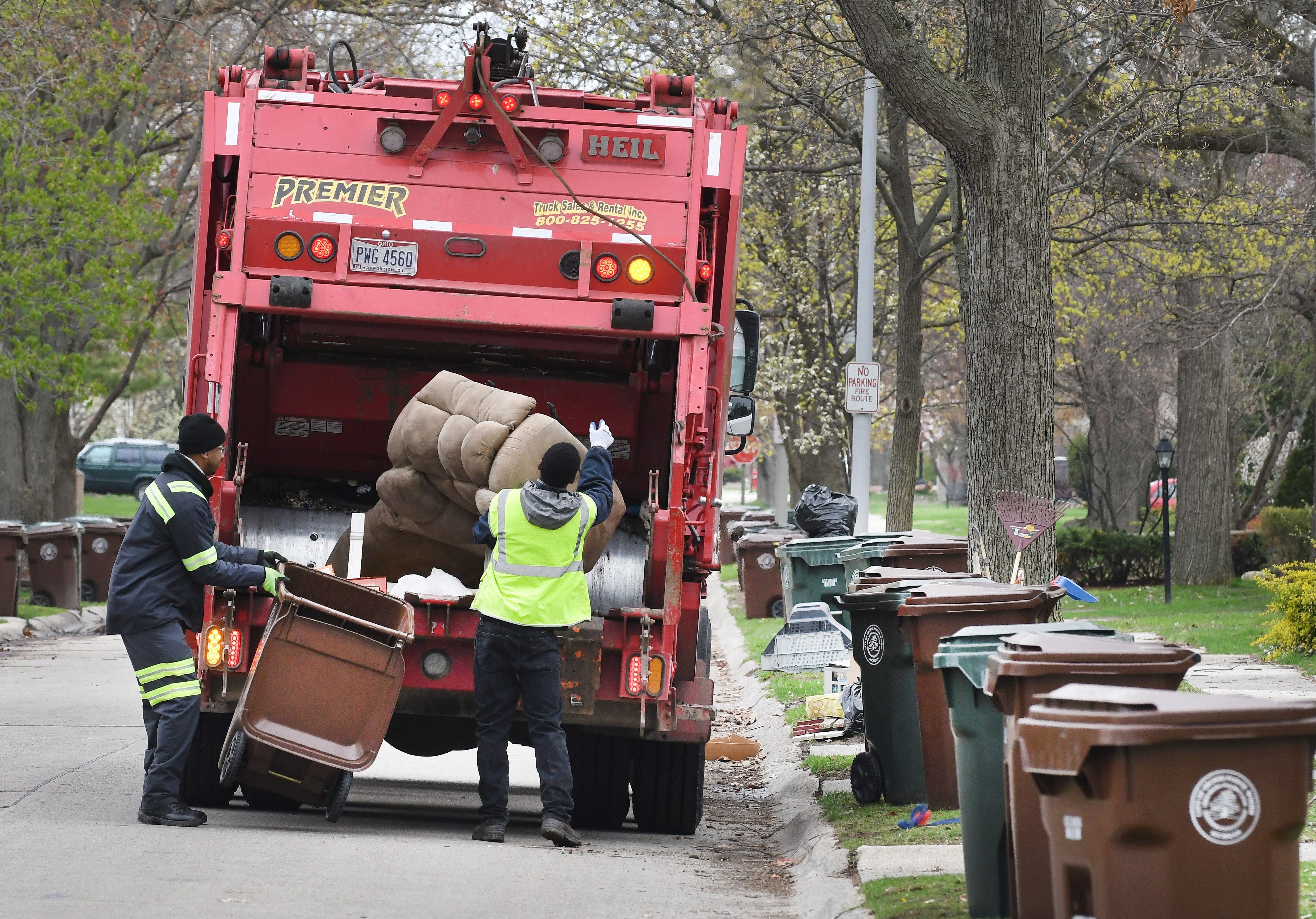 A trash collection crew works on Hampton Road in Grosse Pointe Woods, Monday. Contractor Green for Life, the city said, now must travel further to empty its trucks, delaying their progress.