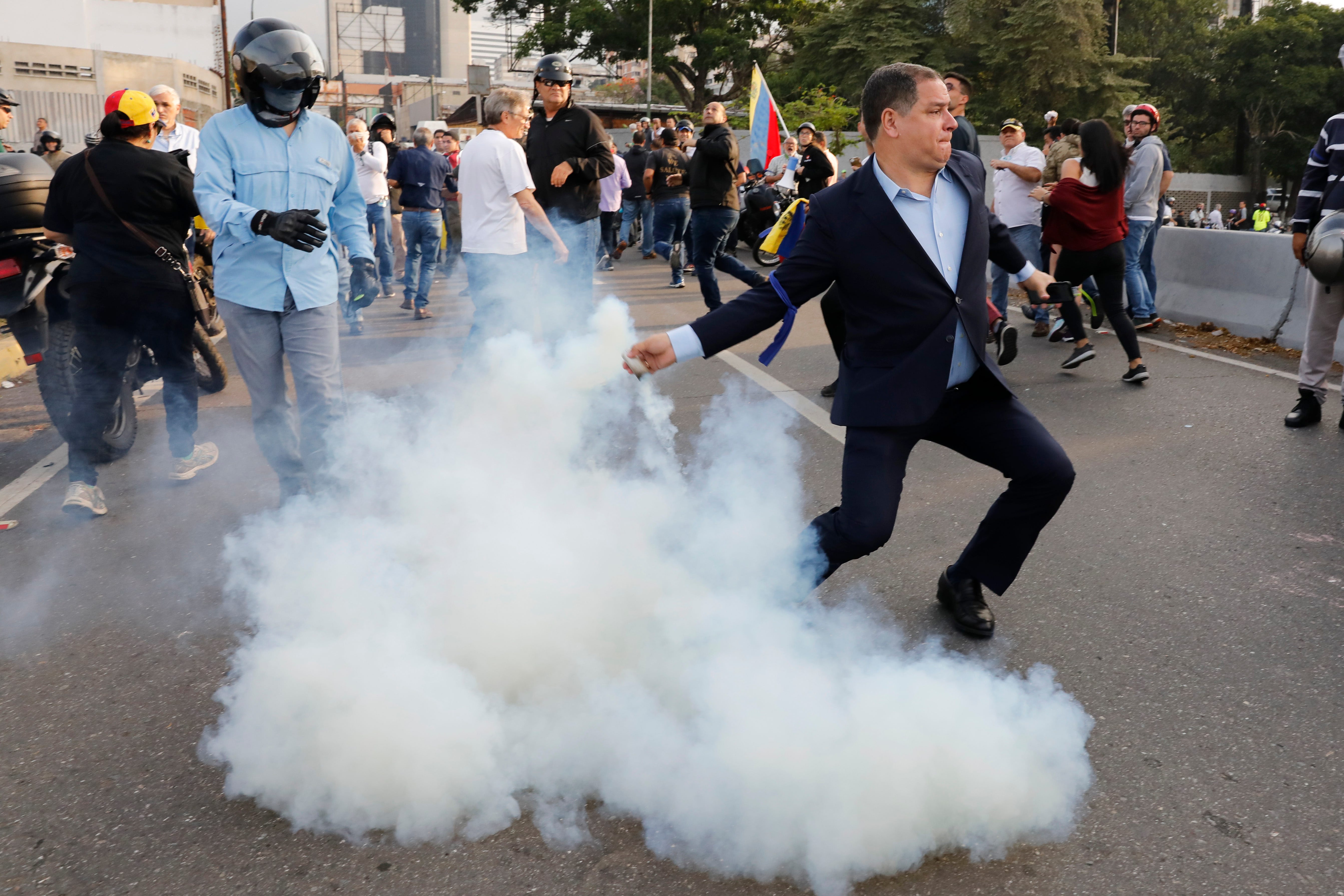 An opponent of Venezuela President Nicolas Maduro returns a tear gas canister to soldiers who launched it outside La Carlota air base in Caracas, Venezuela, April 30, 2019.
