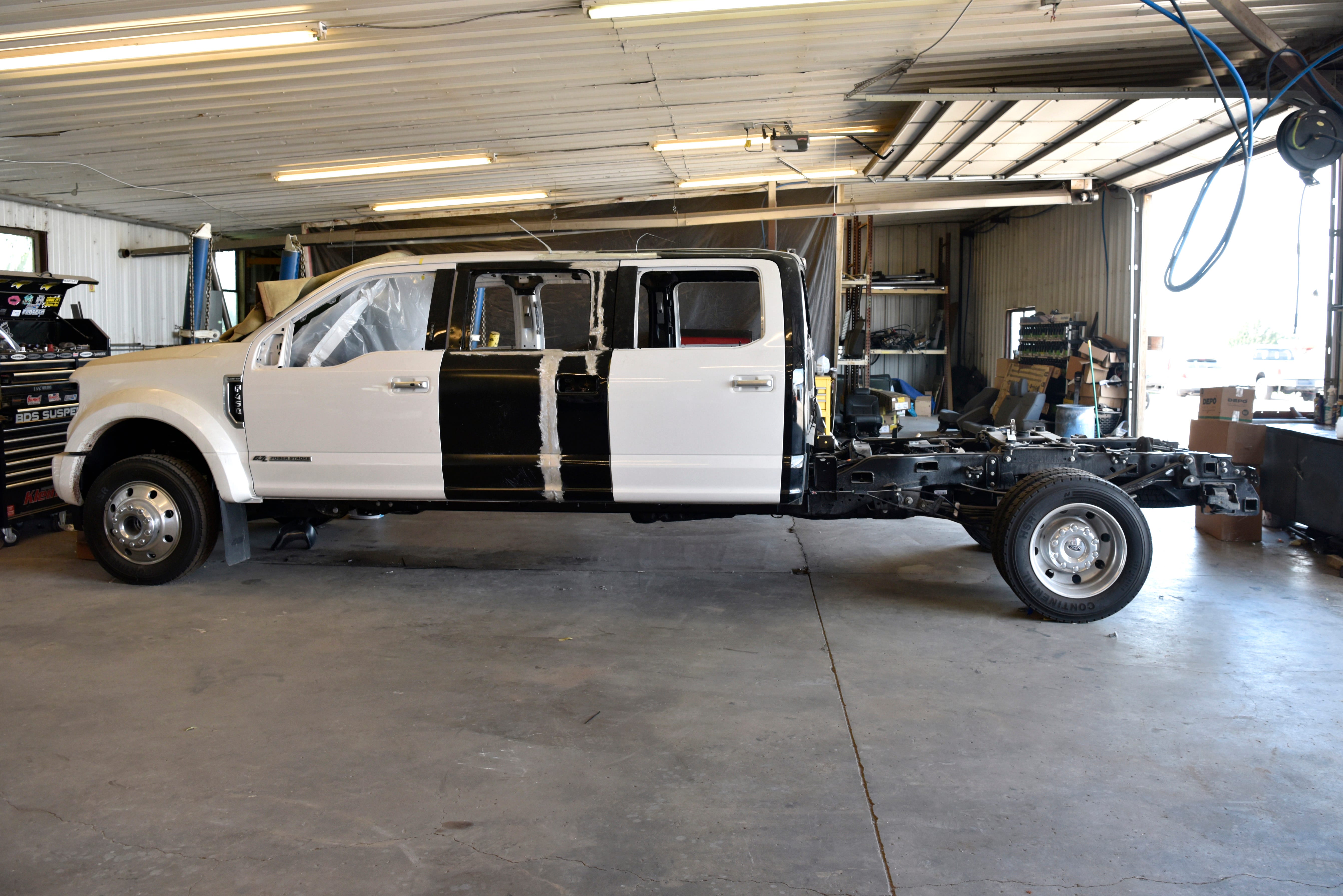A custom six door Ford Excursion waits to be outfitted with a truck bed.