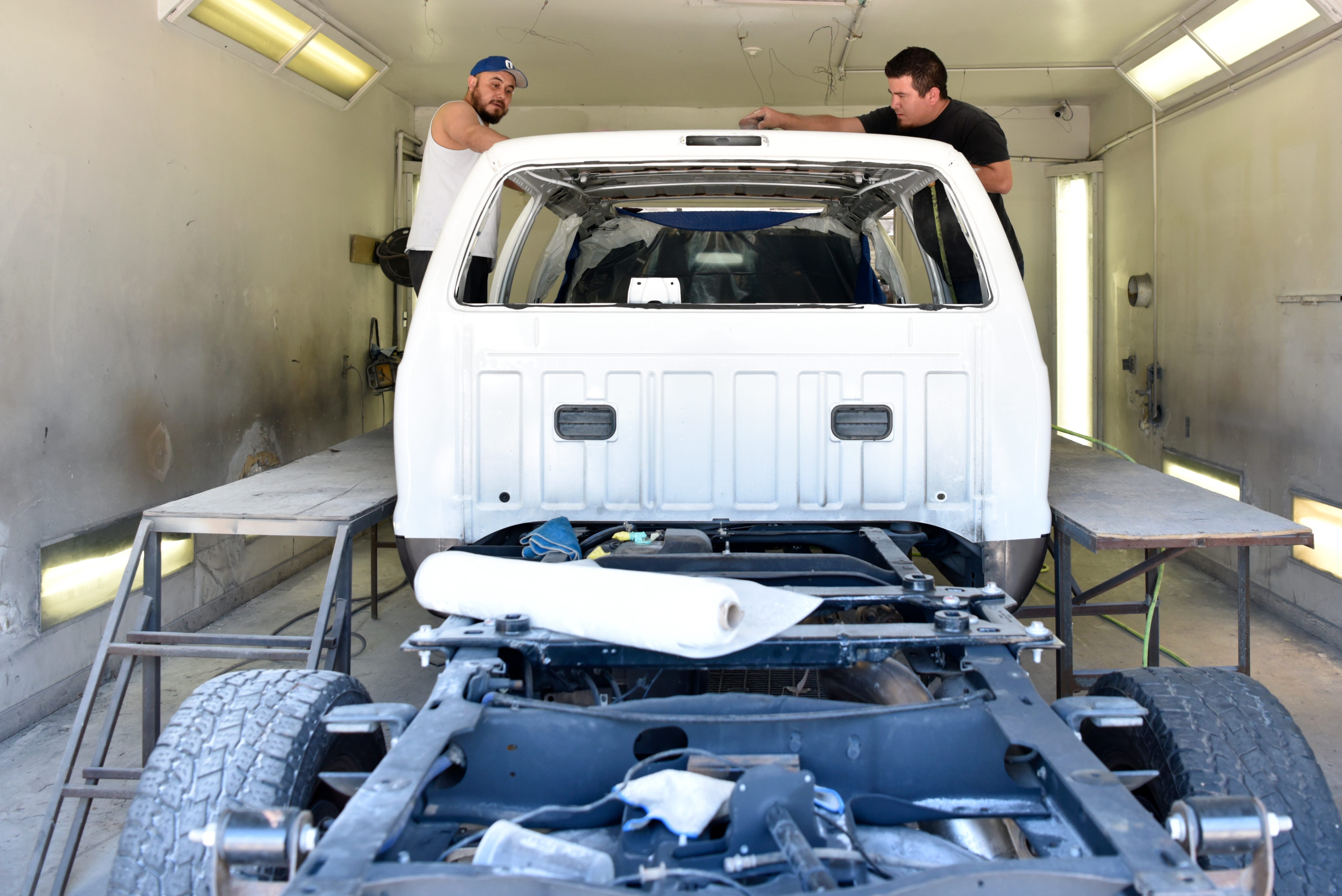 Ulises Rivera, left, and Edwin Ramirez prepare a custom built Ford Excursion for paint at Custom Autos By Tim in Guthrie, Oklahoma on April 26, 2019.