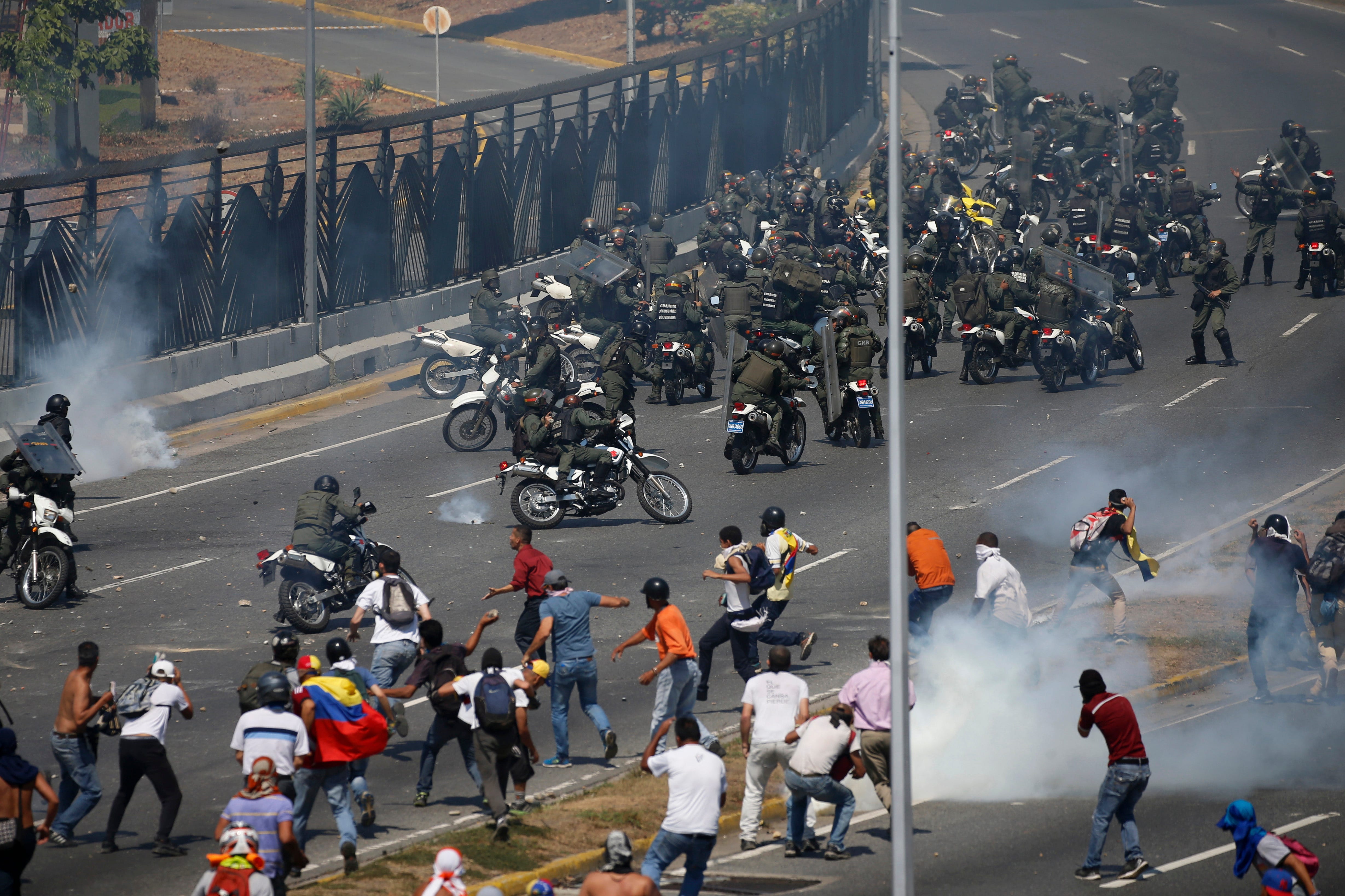 Opponents to Venezuela's President Nicolas Maduro confront loyalist Bolivarian National Guard troops firing tear gas at them, outside La Carlota military airbase in Caracas, Venezuela, Tuesday, April 30, 2019.