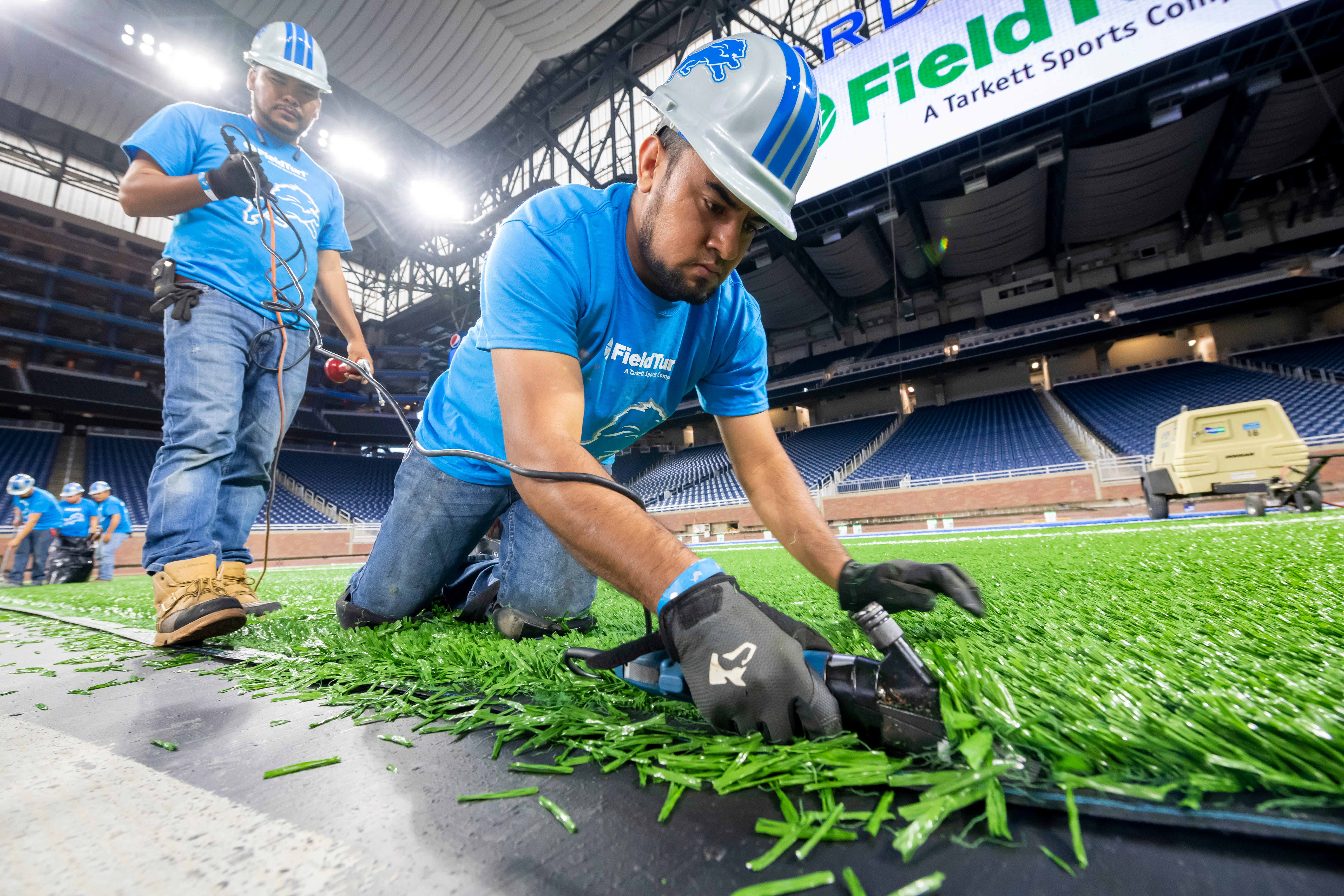 FieldTurf employee Jesus Casteneda uses sheep shearers to trim the edge of a piece of a new playing surface during installation at Ford Field in Detroit, on Thursday, May 9, 2019. The entire field is being replaced with new FieldTurf with work estimated to be finished at the end of May.