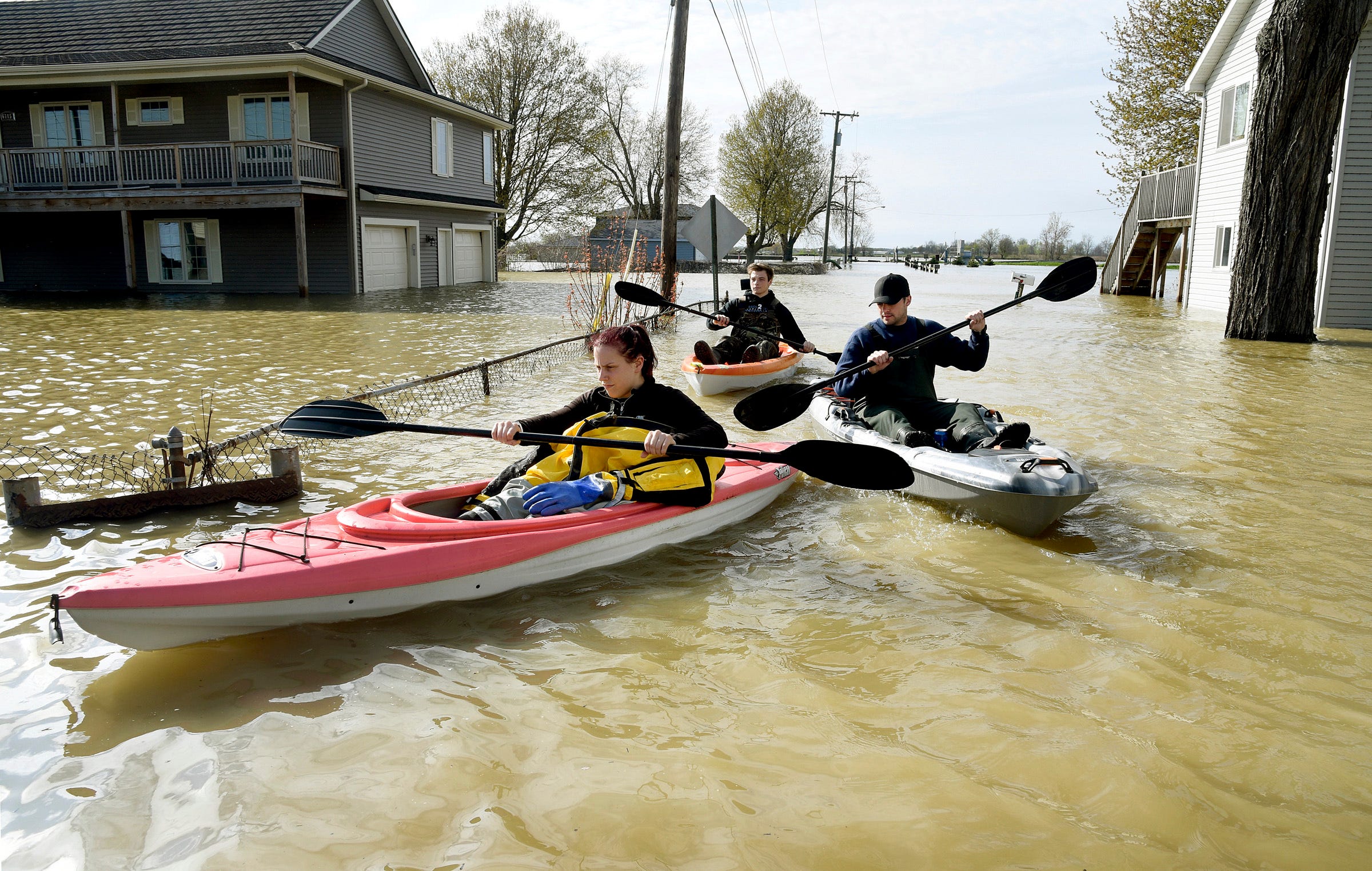 Estral Beach firefighters Courtney Millar, Eric Bruley and Chase Baldwin kayak down Lakeshore Drive in the south end of Estral Beach in Berlin Township last month.