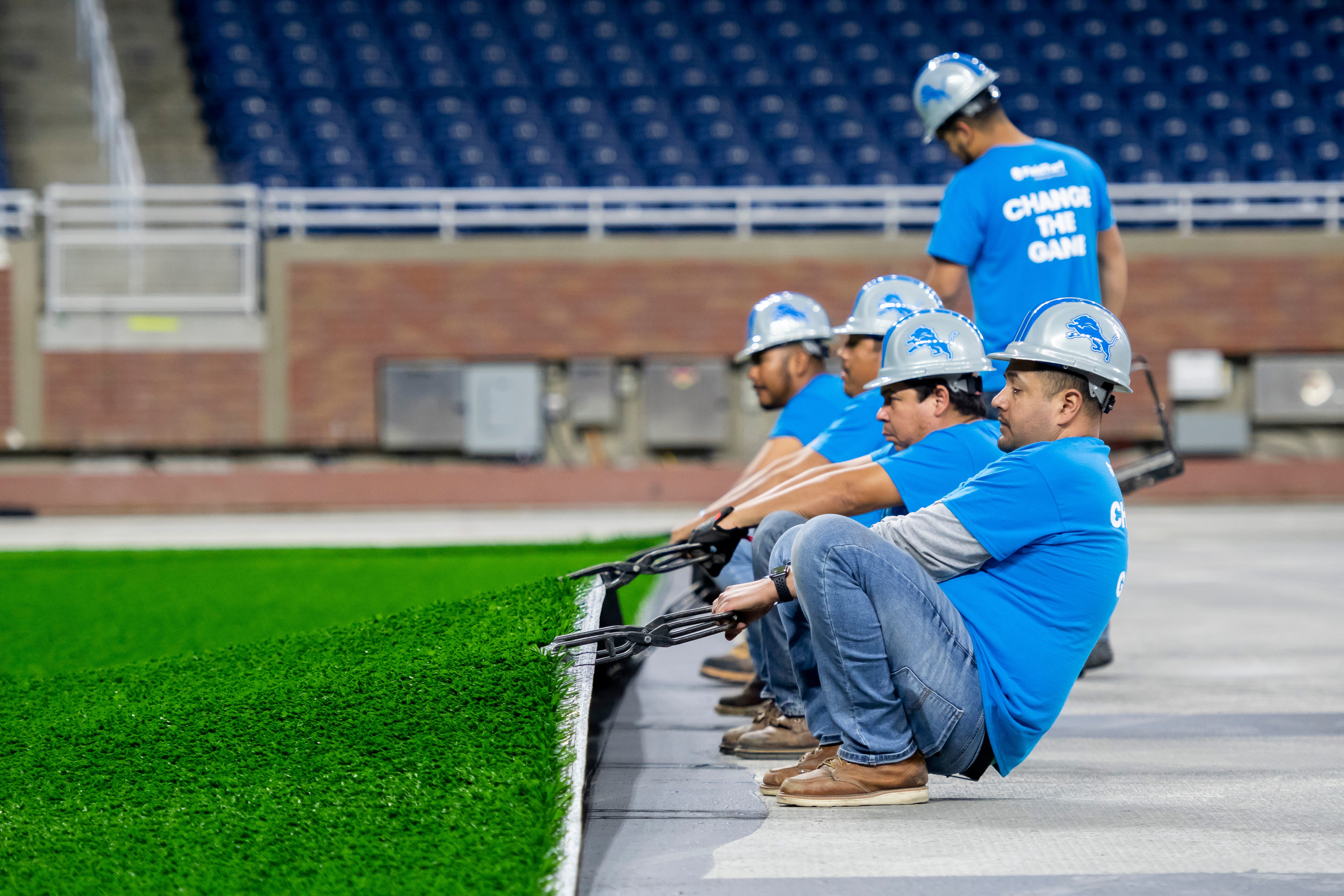 FieldTurf employees stretch the playing surface while installing it at Ford Field.