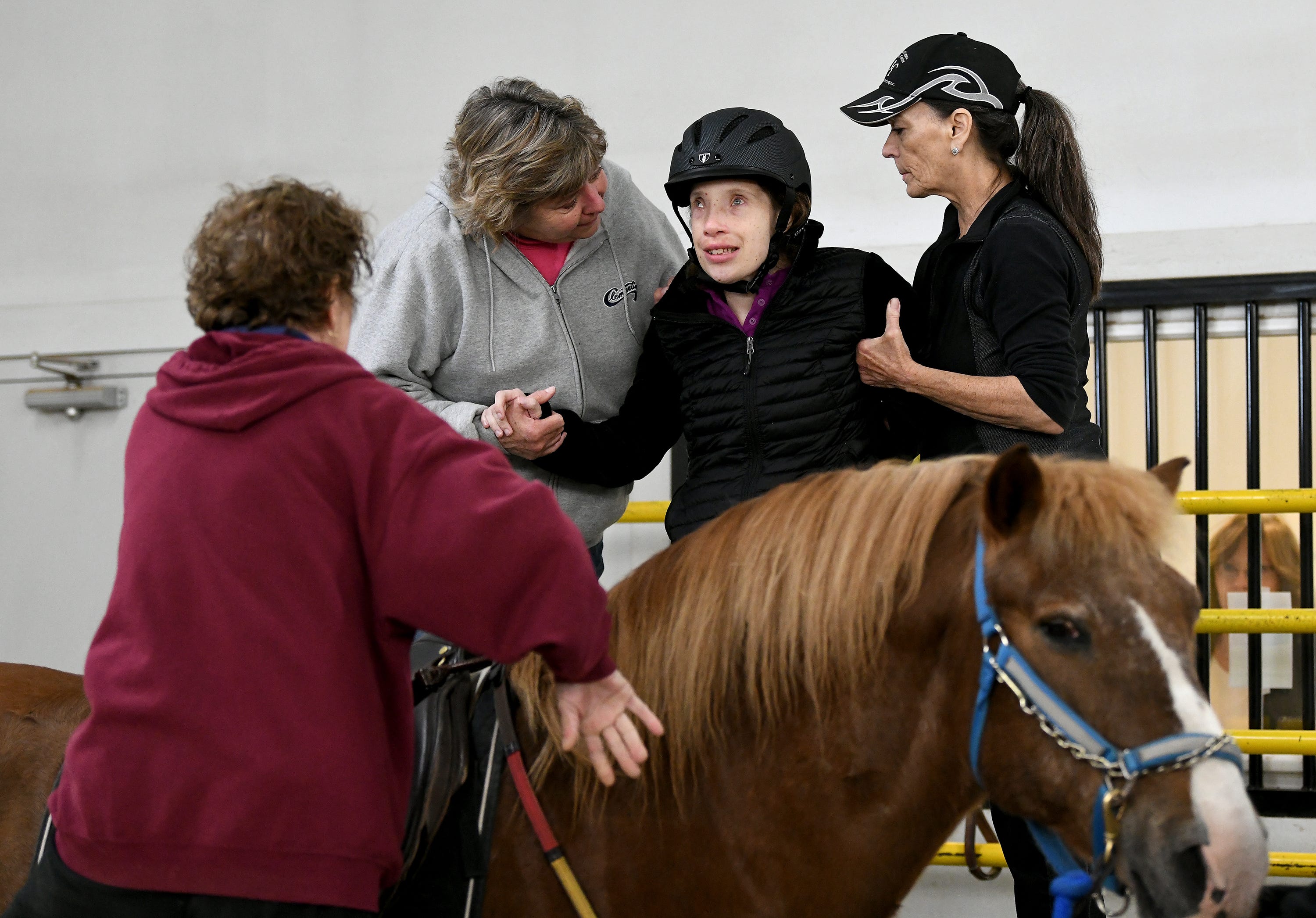 Jan Vescelius, right, Program Director and Head Instructor of Therapeutic Riding Inc., helps rider Elizabeth Lerchin onto Miko, with the help of volunteers Louise Moore, top left, and Merrily Hart.
