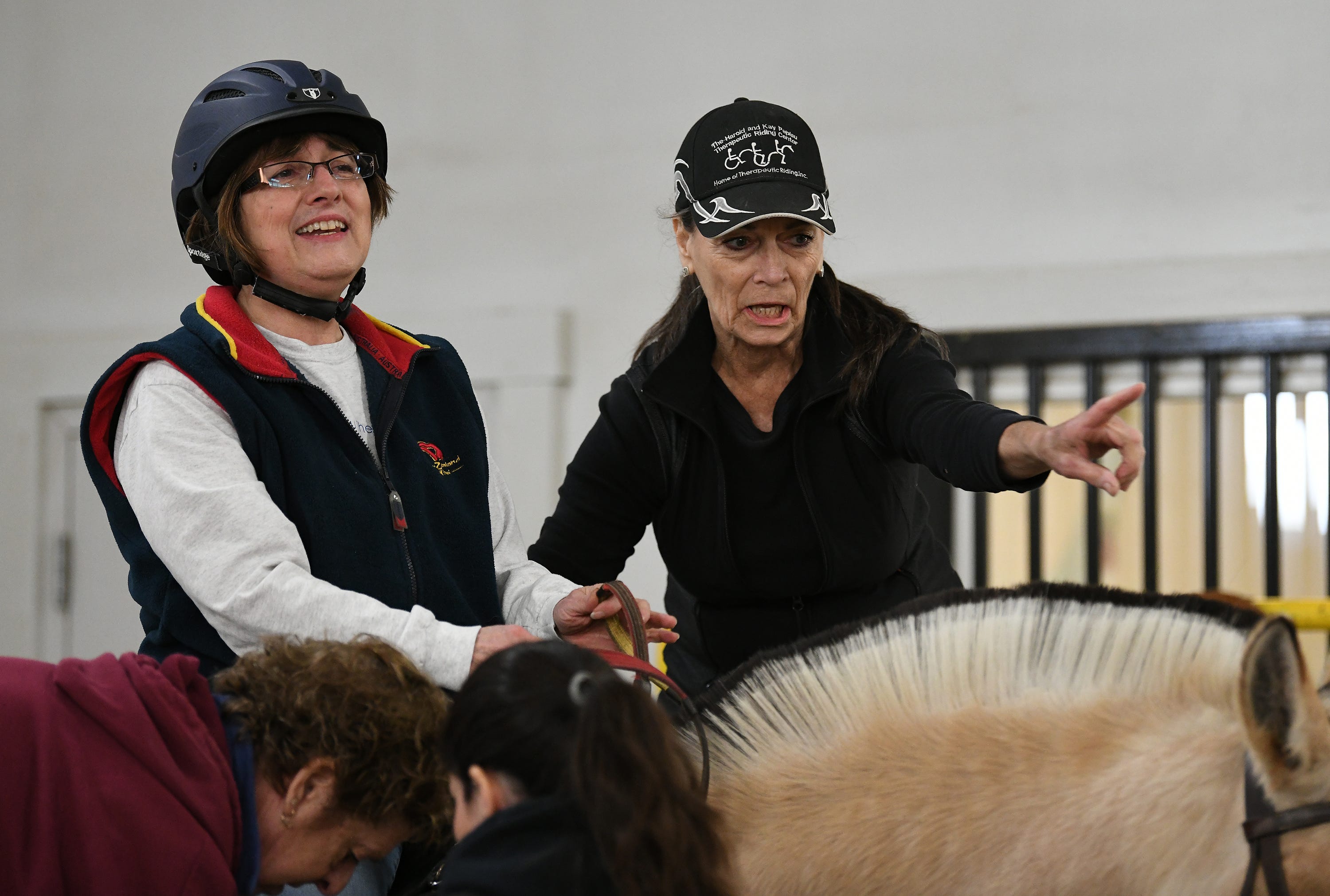 Jan Vescelius, right, Program Director and Head Instructor of Therapeutic Riding Inc., helps rider Deb Swartz onto the horse Sigbjorn, Tuesday morning in Ann Arbor. Therapeutic Riding Inc. just celebrated its 35th Anniversary.