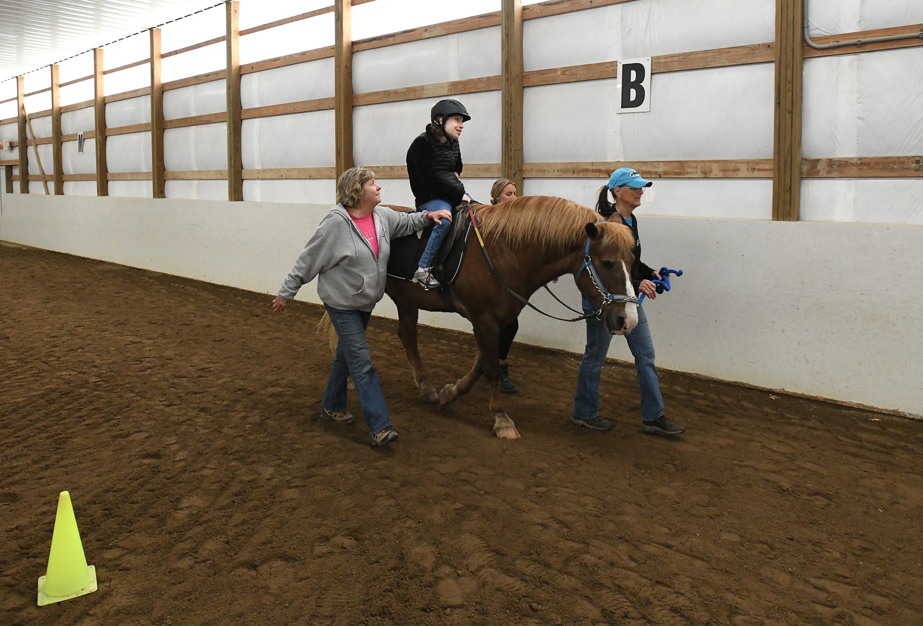 Elizabeth Lerchin rides the horse Miko, with the help of volunteers Louise Moore, left, Pat Whitworth, leading the horse, and Ellie Clark, Tuesday morning in Ann Arbor.