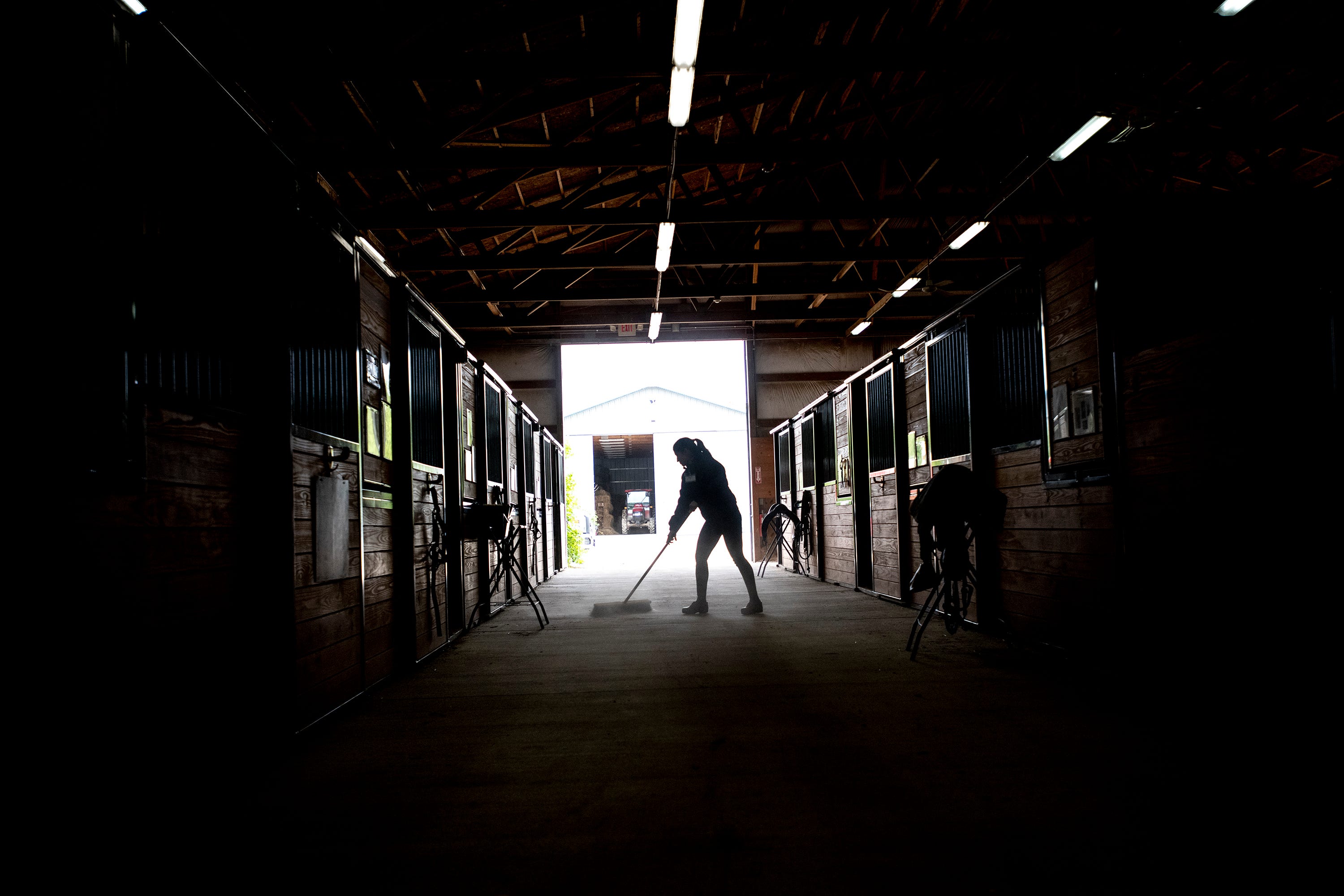 Volunteer Tatiana Bernstein sweeps up the stable floor following Tuesday morning's riding session at Therapeutic Riding Inc. in Ann Arbor.