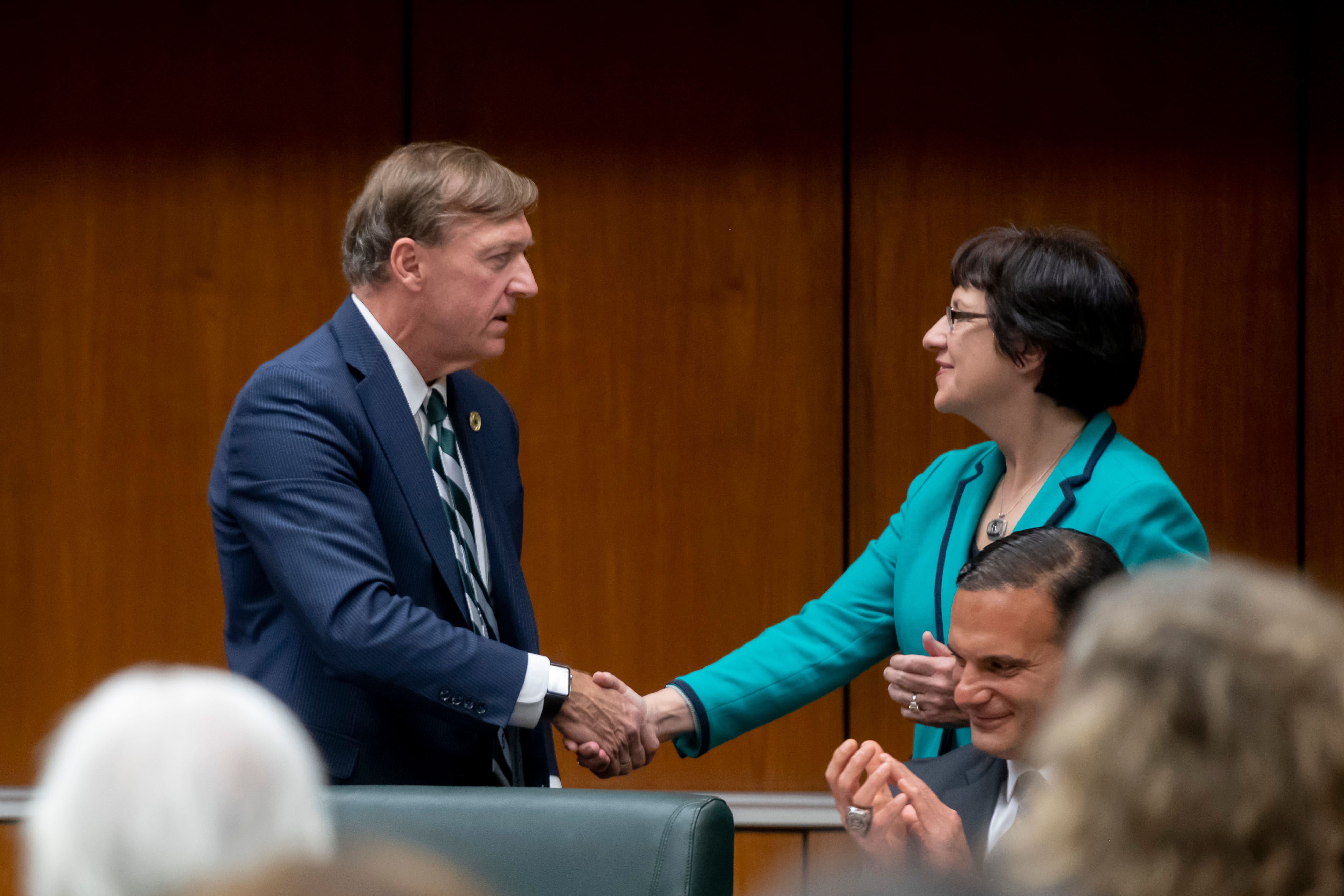Samuel Stanley Jr. and Dianne Byrum, chair of the board of trustees, shake hands after the board voted to elect him Michigan State University's 21st president, May 28, 2019.