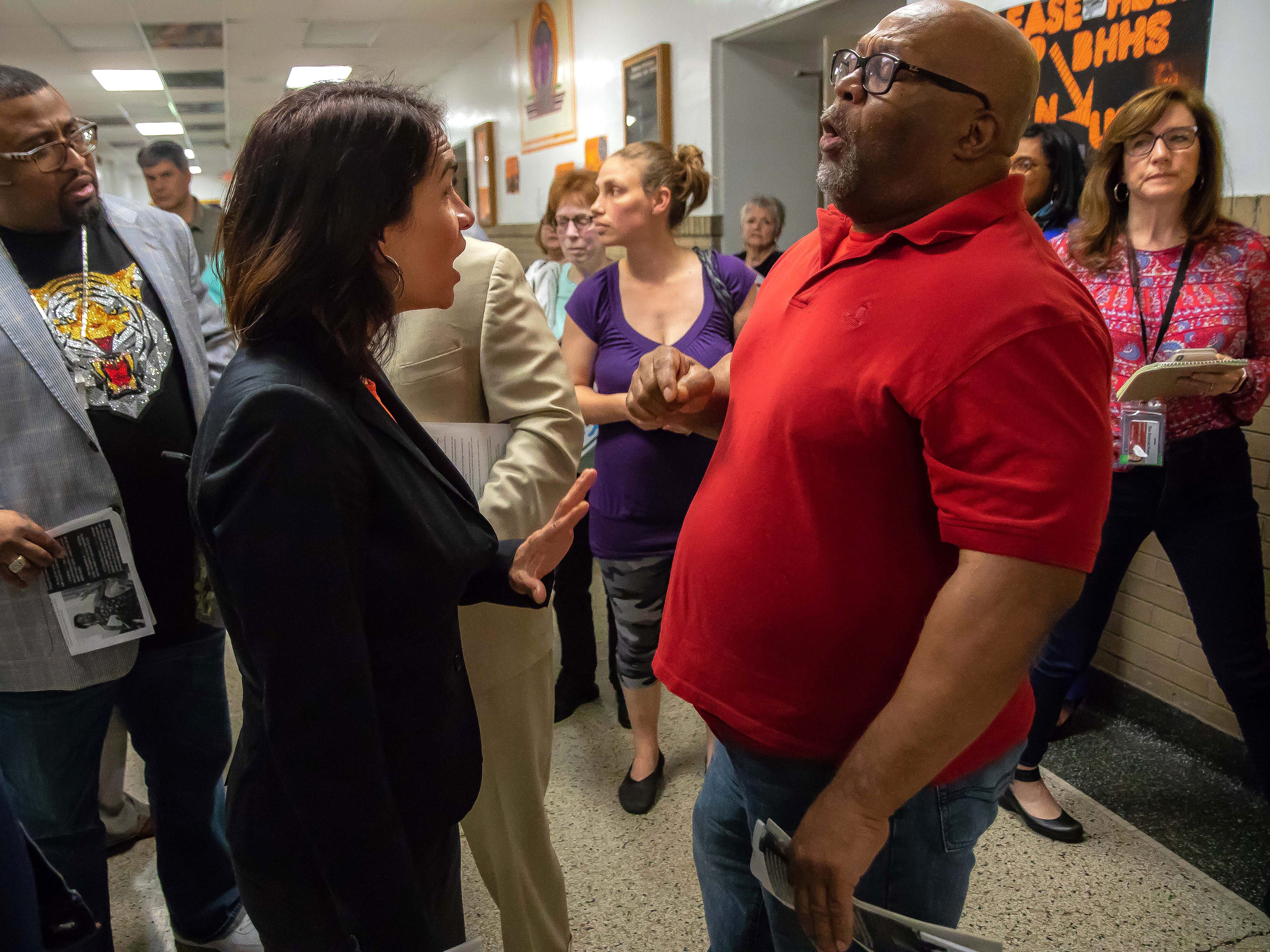 Poppy Sias-Hernandez, regional director of community affairs for Gov. Gretchen Whitmer, talks with local minister Don McAfee at Benton Harbor High School, which the state says must close to salvage the struggling district.