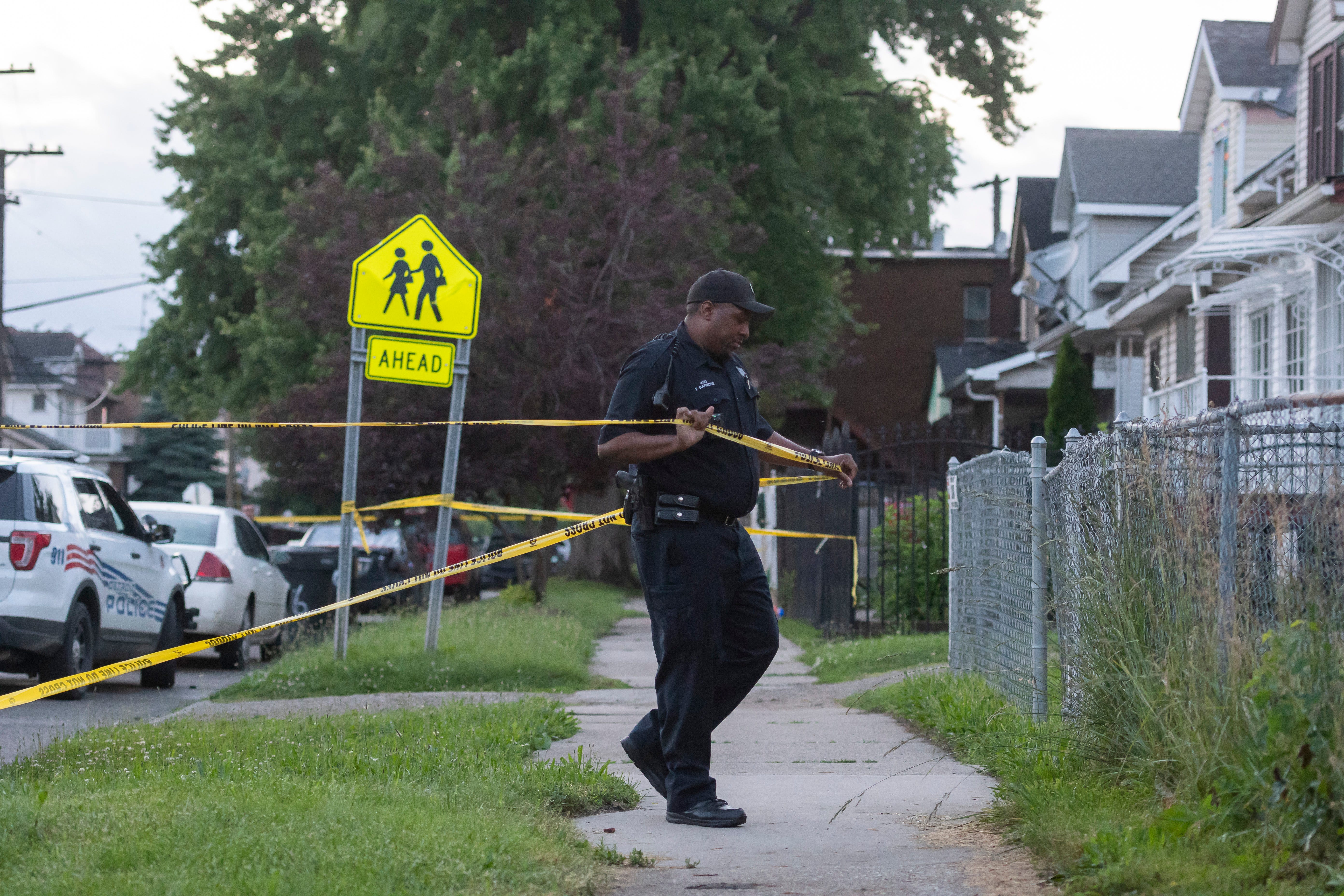 A Detroit police officer secures the scene with tape during the investigation of a shooting on the 2400 block of Honorah, in Detroit, June 20, 2019. The attempted robbery on the city's southwest side left the suspect dead and a 15-year-old seriously injured.