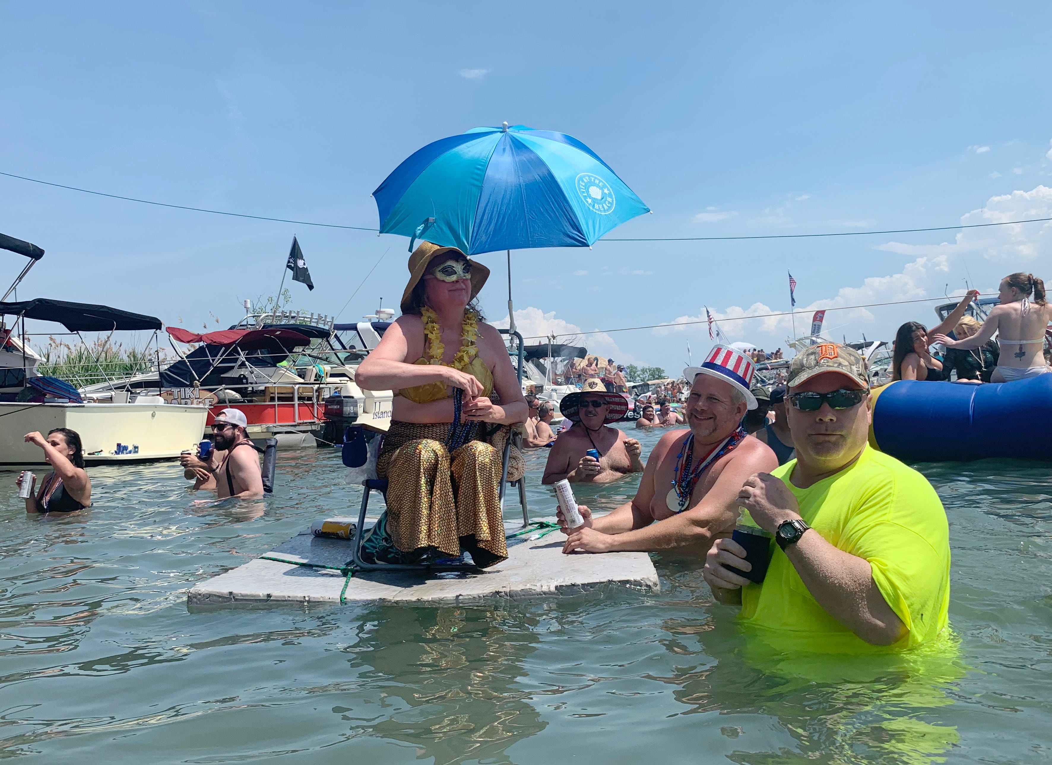 A Jobbie Nooner reveler dressed as a mermaid floats in the shallow water surrounding Gull Island.