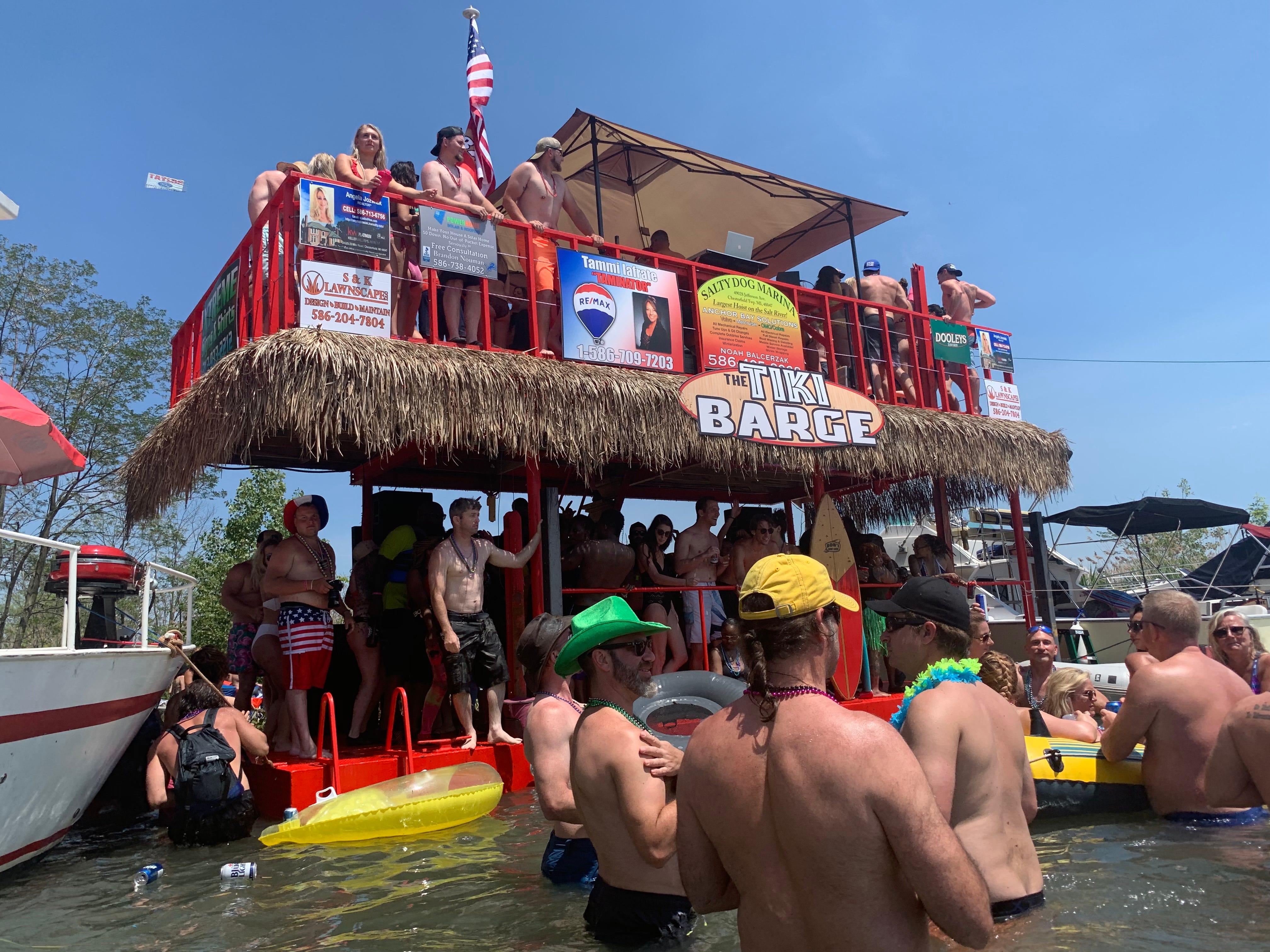 Jobbie Nooner revelers congregate in waist-high waters surrounding the Tiki Barge party boat on what was a beach area in previous years... eliminated this year by high lake water levels on Lake St. Clair at Gull Island.