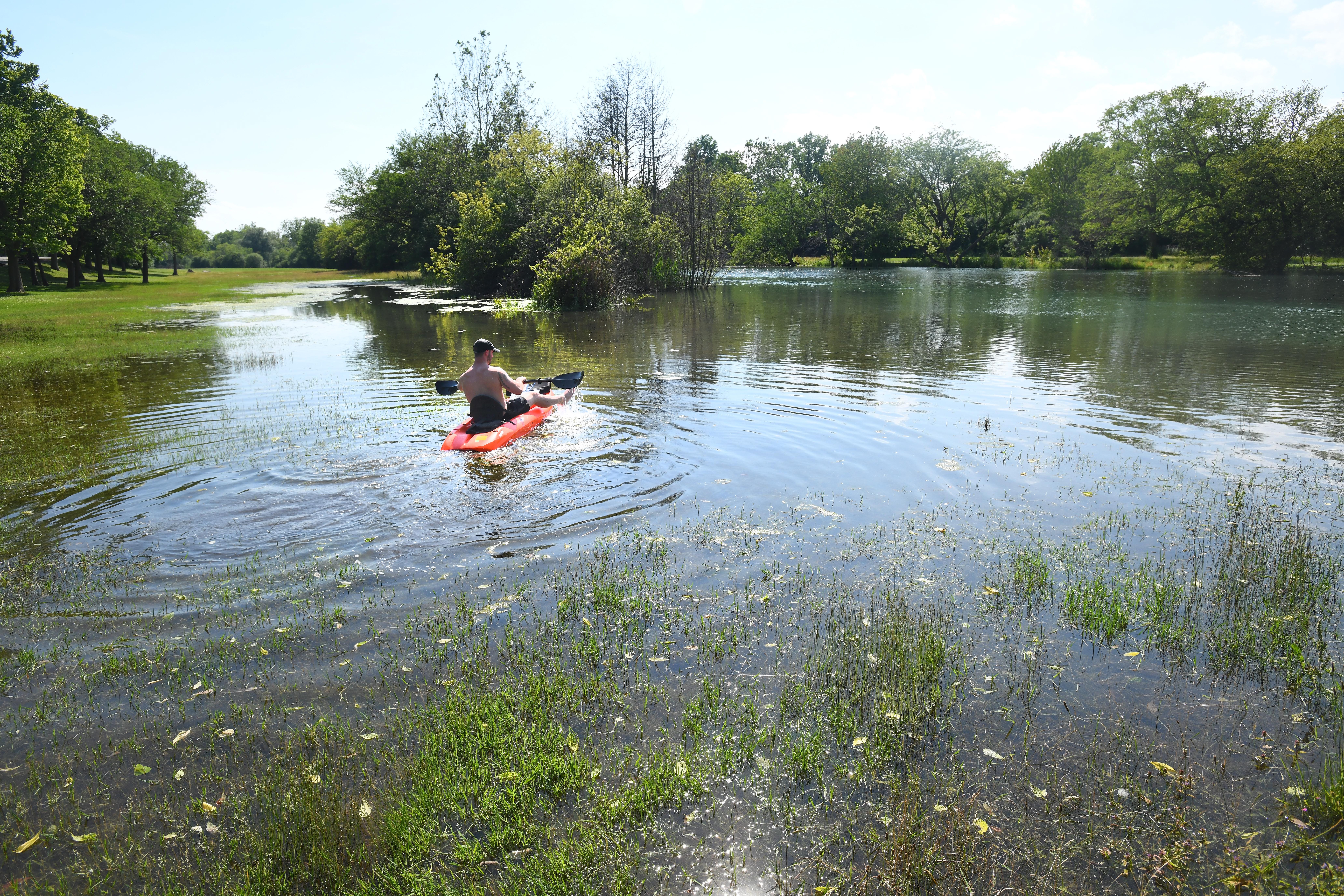 Brian Adam of Romulus paddles across what is normally a field near the banks of the Trenton Channel in Elizabeth Park in Trenton, Michigan on July 1, 2019.