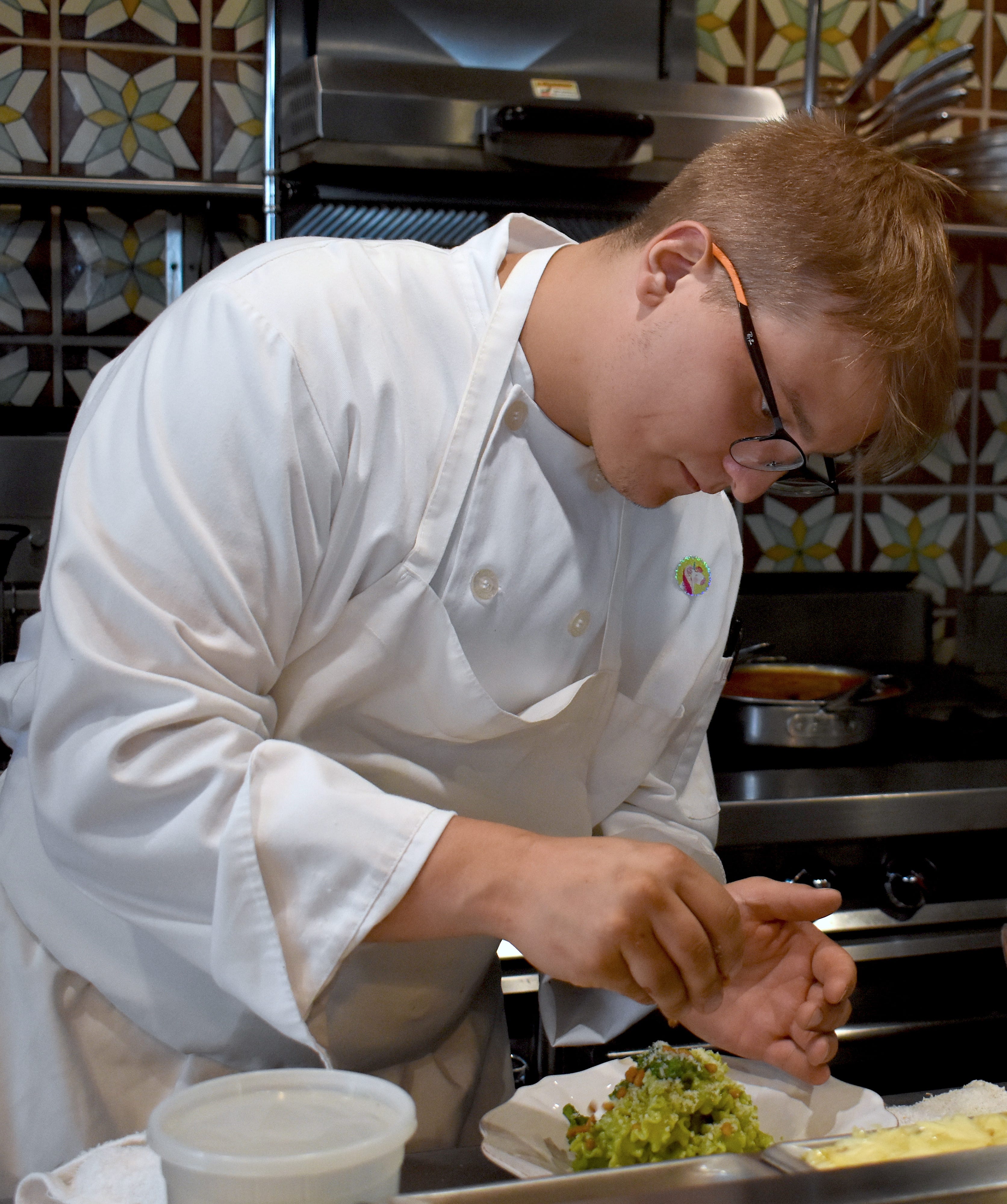 In the open kitchen, pasta cook Devin Salbut plates a dish of malfadini, rapini pesto, sweet and sour peppers and pine nuts.