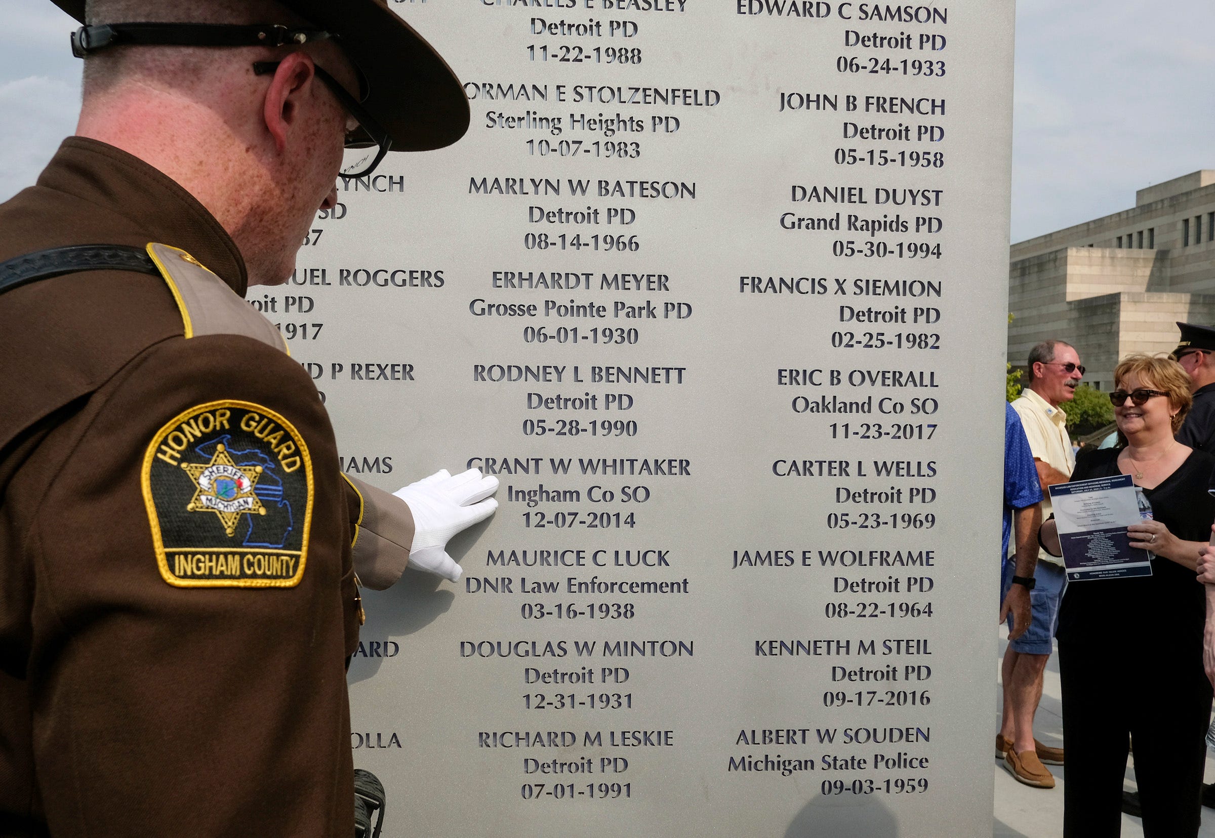 Ingham County Sheriff Deputy Matt Hutting touches the name of Grant W. Whitaker who died in the line of duty in December 2014 at the Michigan Law Enforcement Officer's Memorial Monument Dedication and Memorial Service Saturday in Lansing.