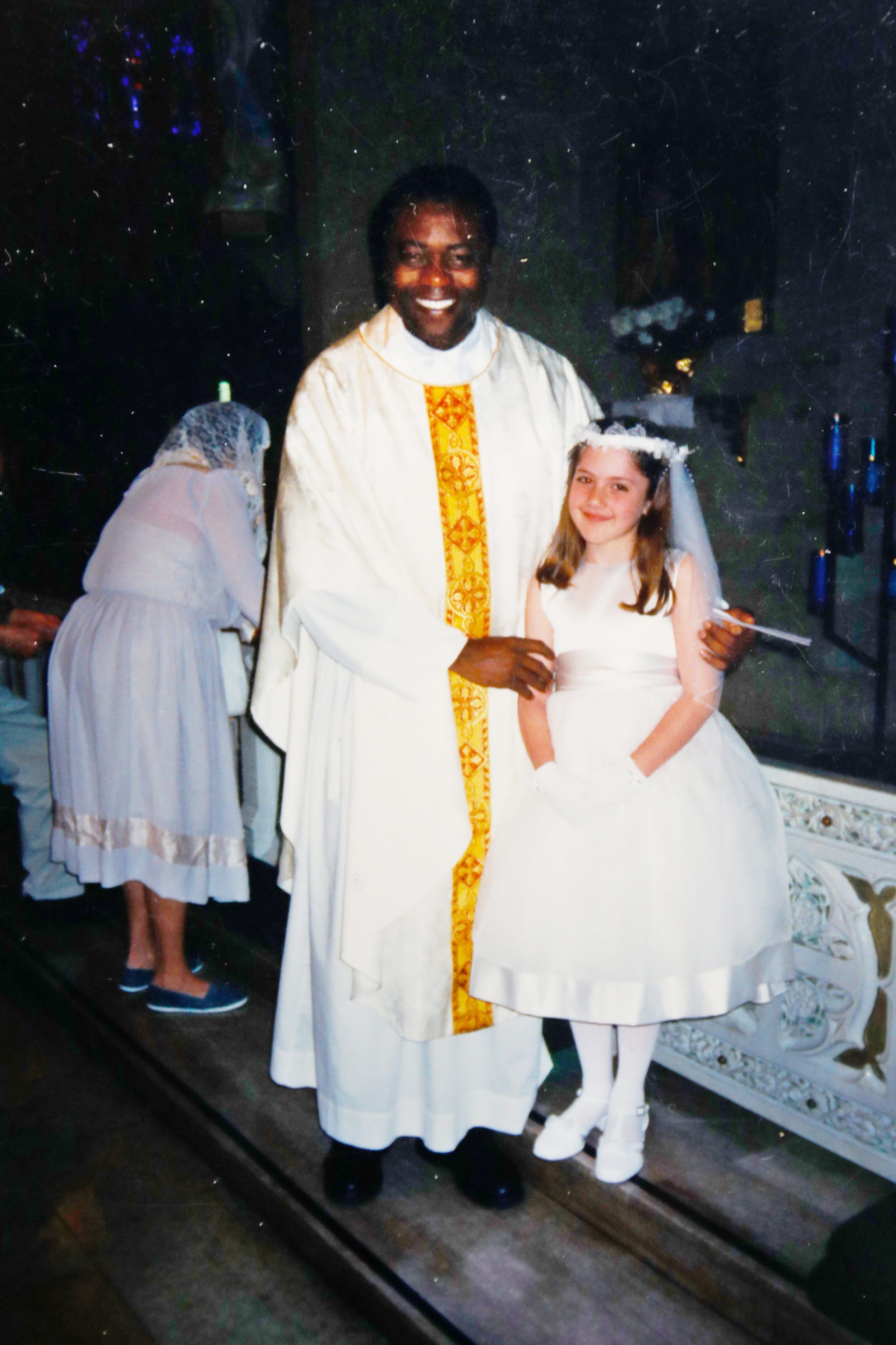 This undated photo provided by Mary Rose Maher shows her as a child standing with the Rev. Komlan Dem Houndjame at The Assumption of the Blessed Virgin Mary Church in Detroit. Two years after arriving at The Assumption of the Blessed Virgin Mary Church in 1999, Detroit Archdiocese officials said they asked Houndjame to return to his home country, Togo, after learning of accusations of sexual misconduct against him in Detroit and at an earlier posting in Florida. Instead he went to a treatment facility in St. Louis. In 2002, Detroit police arrested him and charged him with sexually assaulting a member of the church ' s choir.