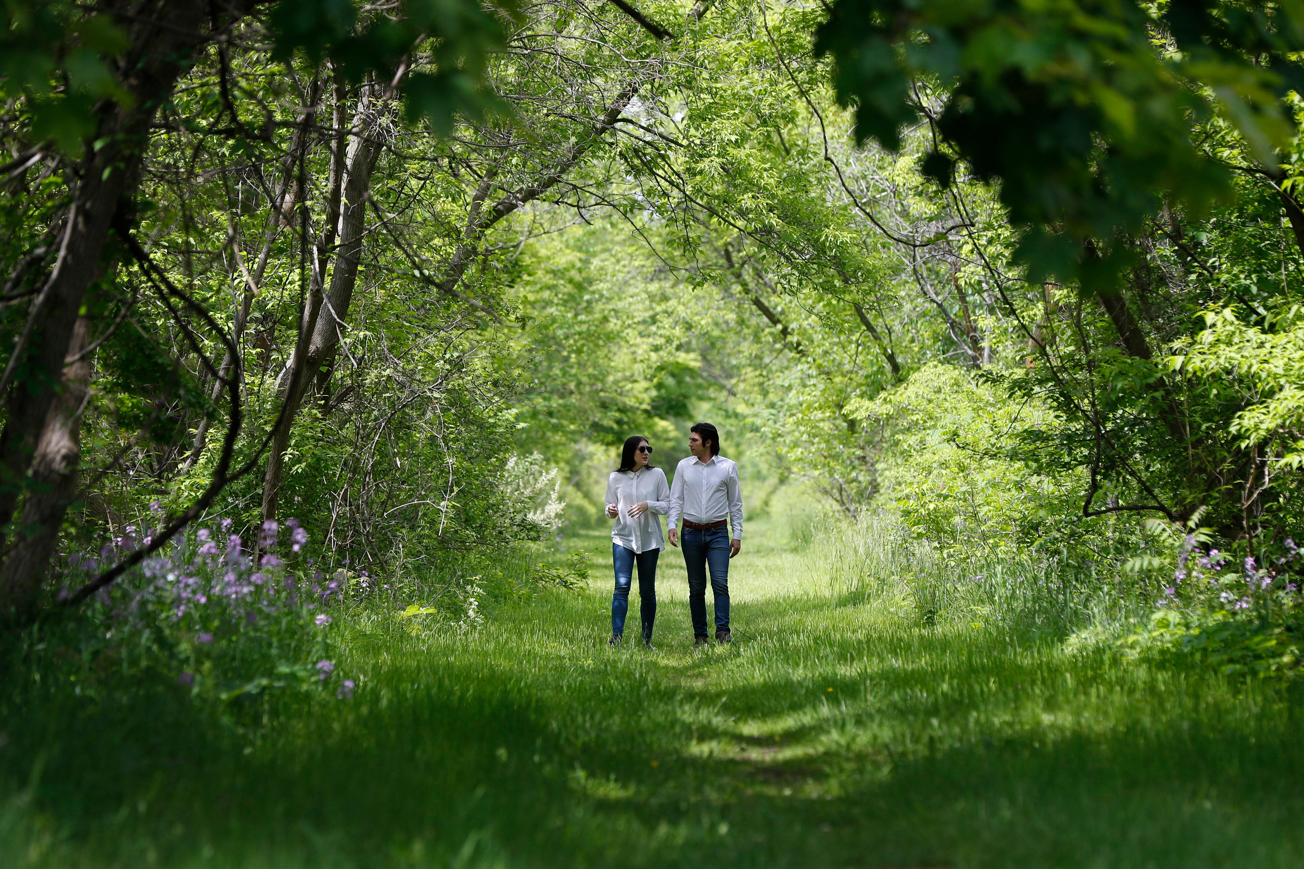 Mary Rose Maher and her fiance, William Chundrlik, walk through woods near a former Opus Bono Sacerdotii location in Dryden, Michigan, on June 5. Opus Bono ' s finances came under scrutiny after authorities were contacted by a once-loyal employee - Maher, the daughter of co-founder Joe Maher - who began questioning the way money was spent.