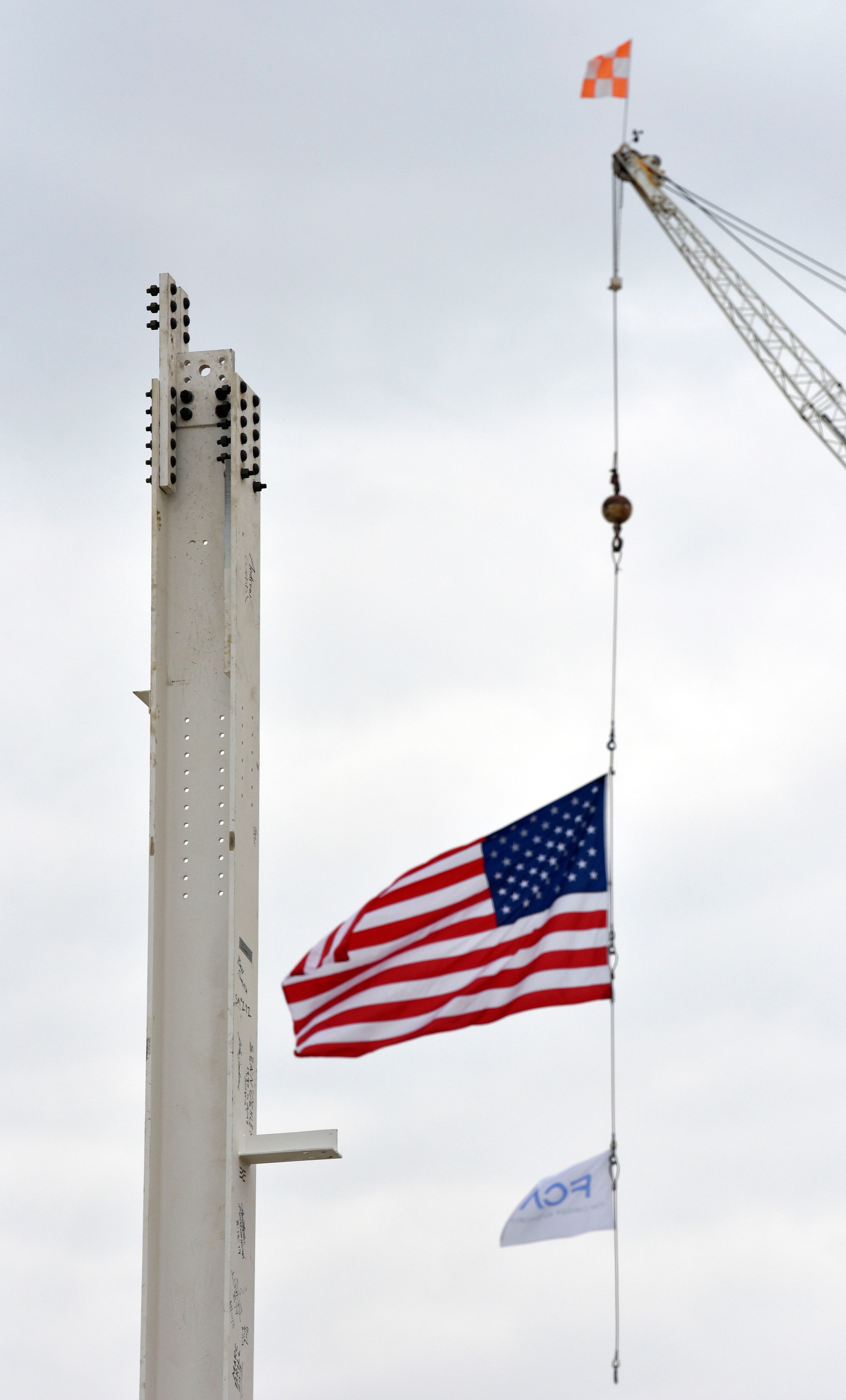 The U.S. flag and FCA flag blow in the breeze after workers set the first vertical column for the new paint shop.