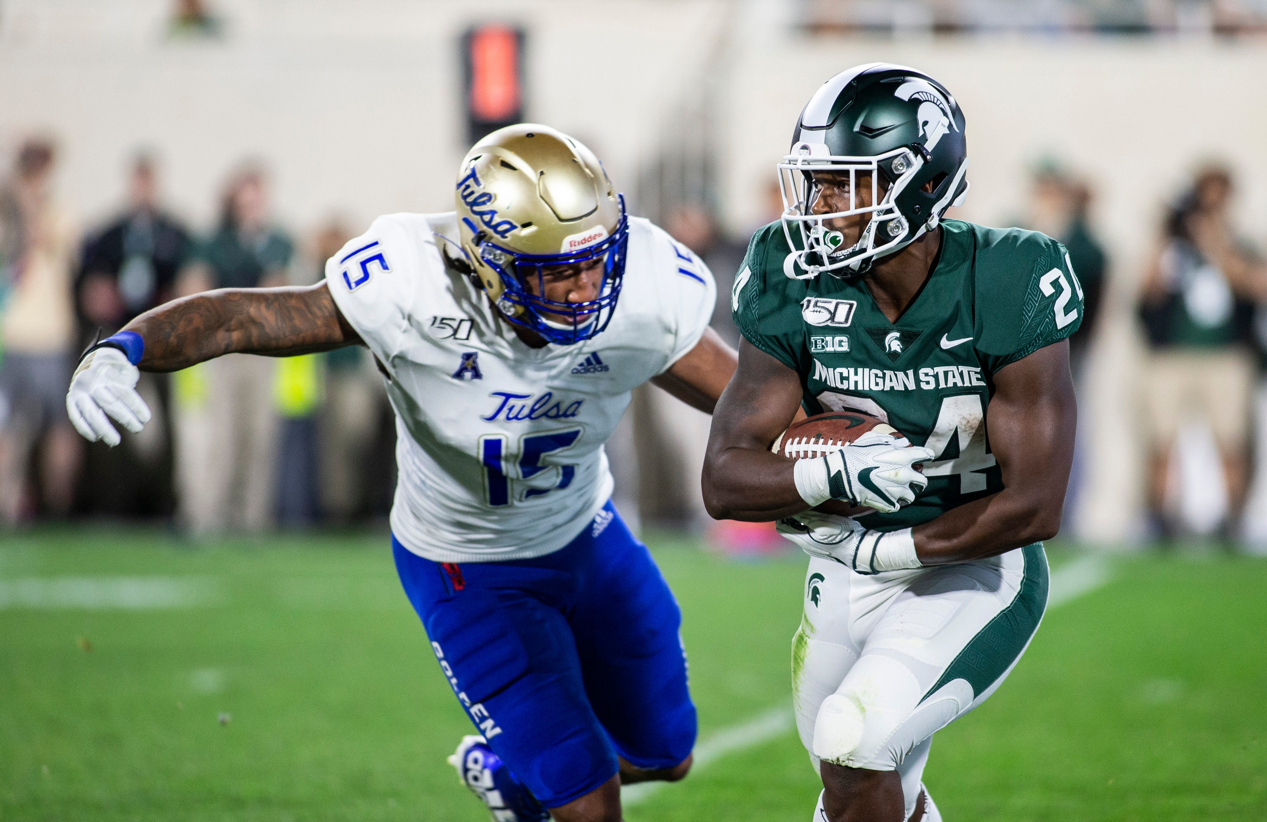 Tulsa defensive end Trevis Gipson, left, attempts a tackle Michigan State running back Elijah Collins during the second half of the season opener in East Lansing.