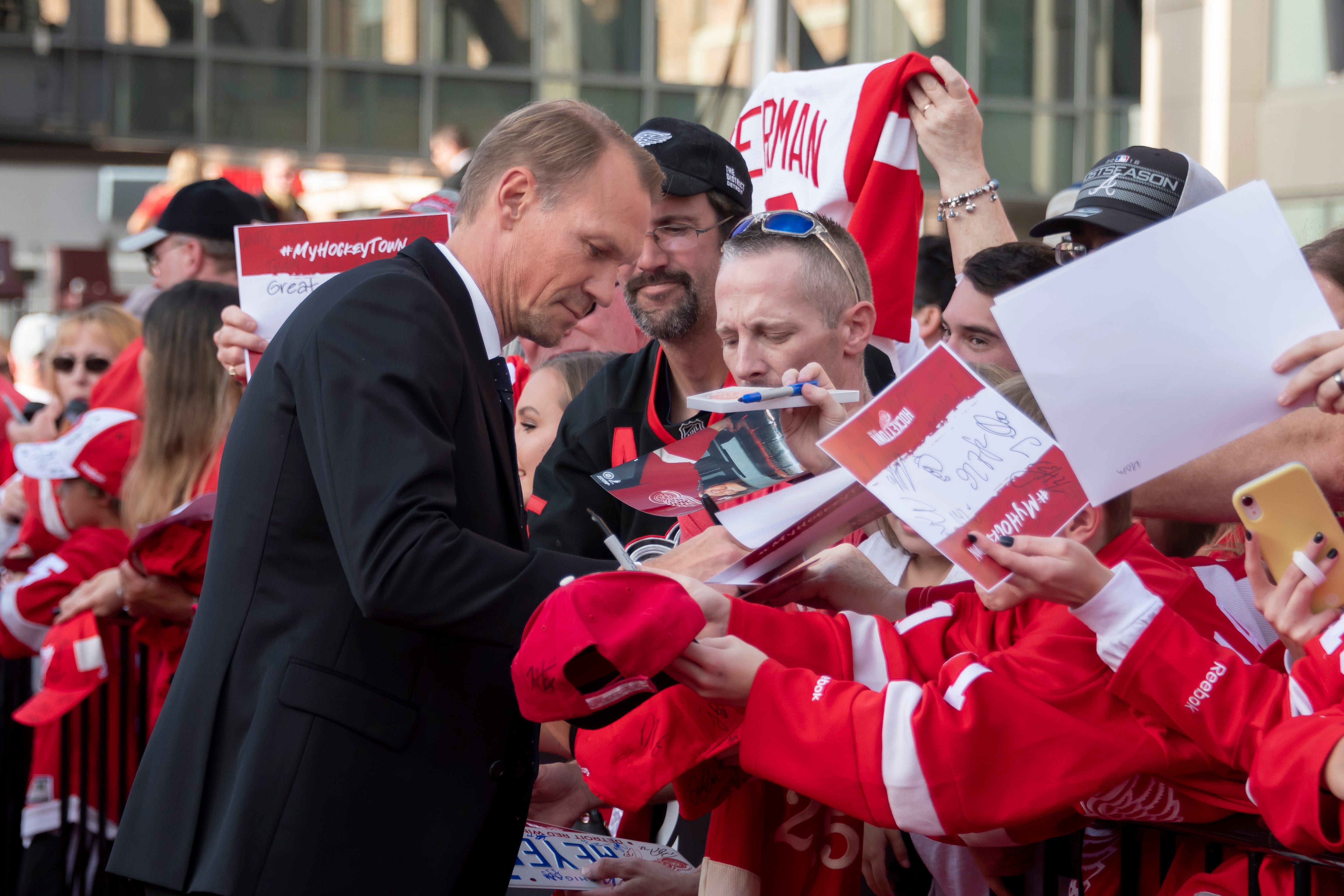 Former Red Wings captain Niklas Lidstrom signs autographs while participating in a red carpet ceremony before the team's home opener against the Dallas Stars.