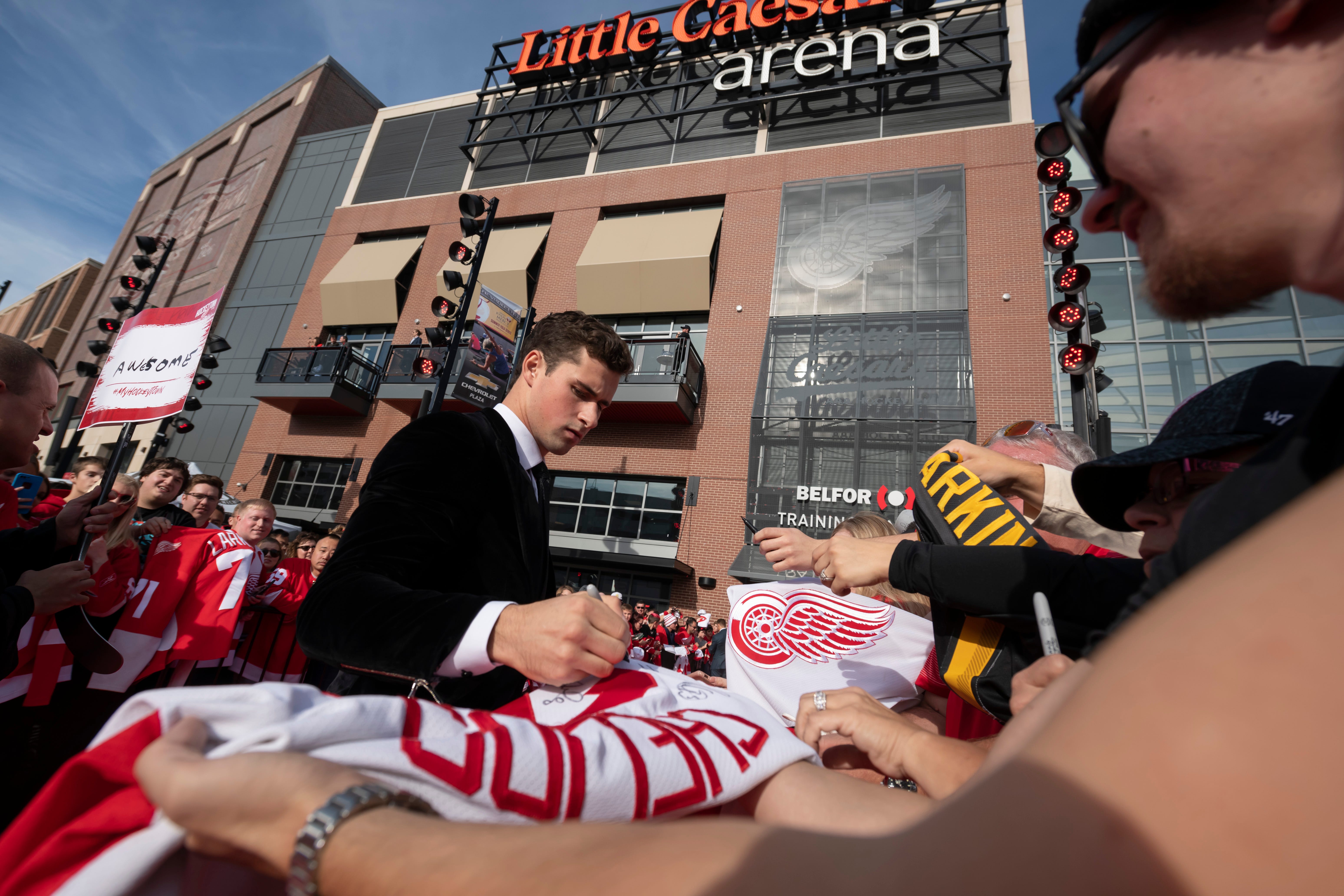 Red Wing Dylan Larkin signs autographs while participating in a red carpet ceremony before the team's home opener against the Dallas Stars.
