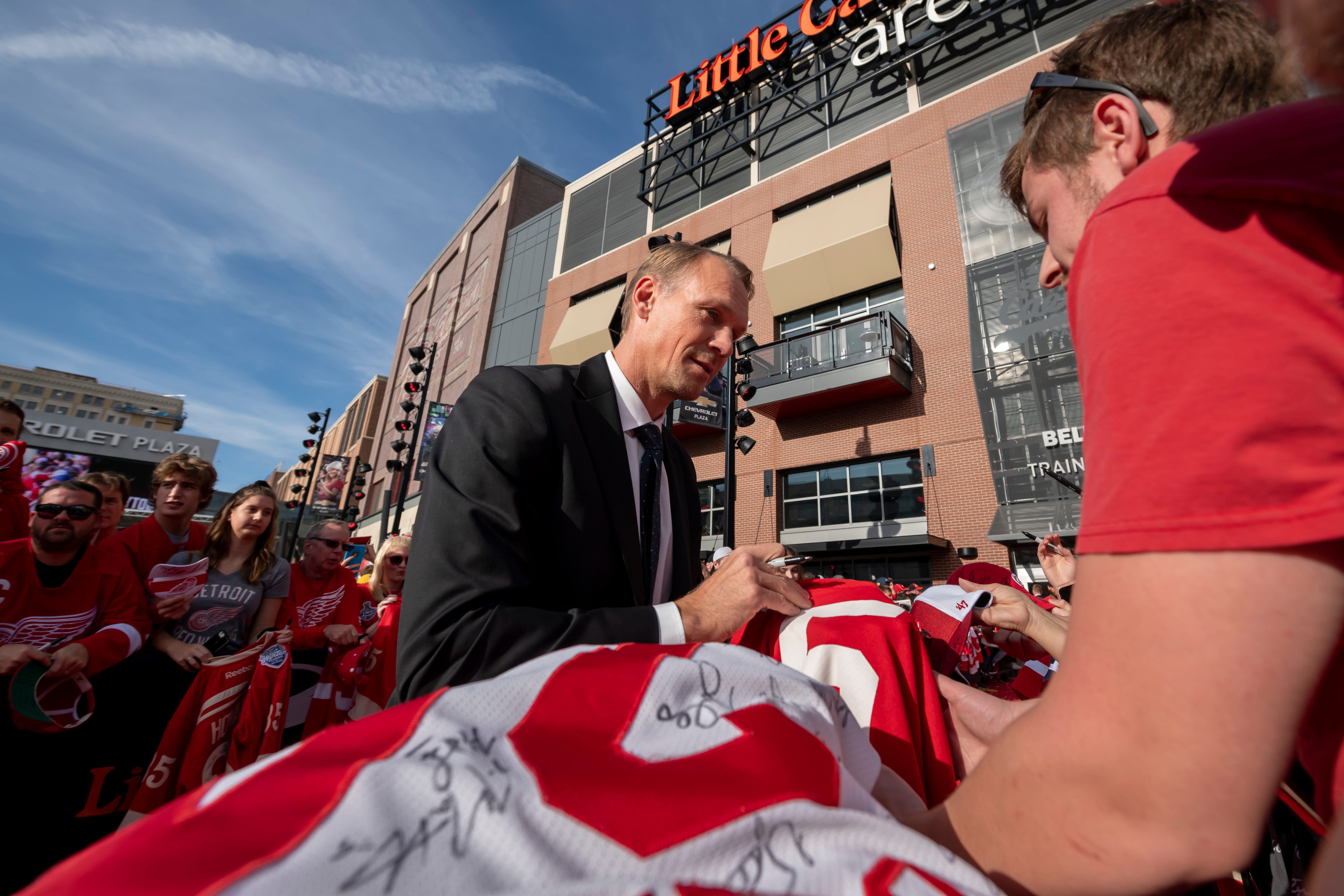 Former Red Wings captain Niklas Lidstrom signs autographs while participating in a red carpet ceremony before the team's home opener against the Dallas Stars.