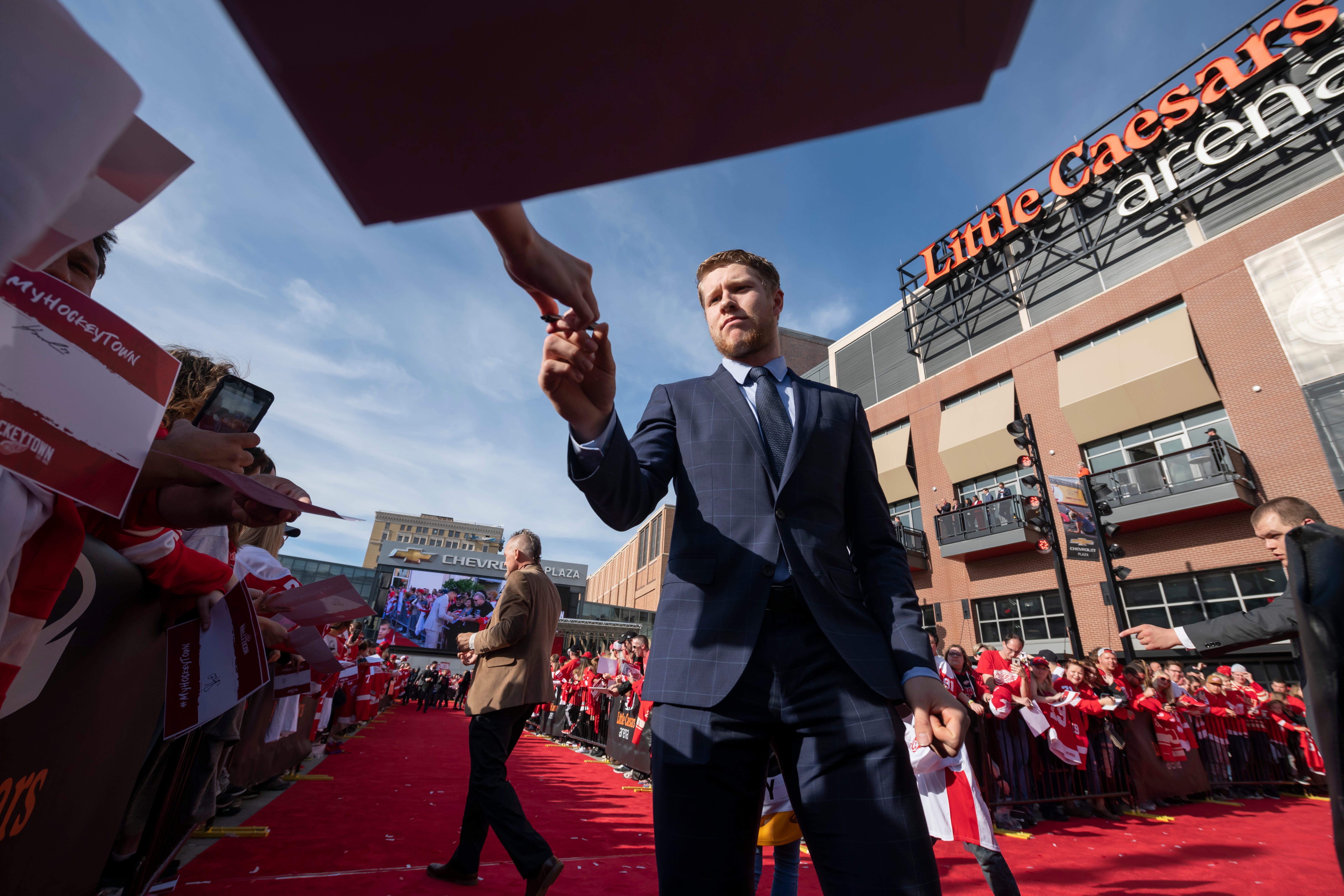 Red Wings defenseman Dennis Cholowski signs autographs while participating in a red carpet ceremony before the team's home opener against the Dallas Stars.