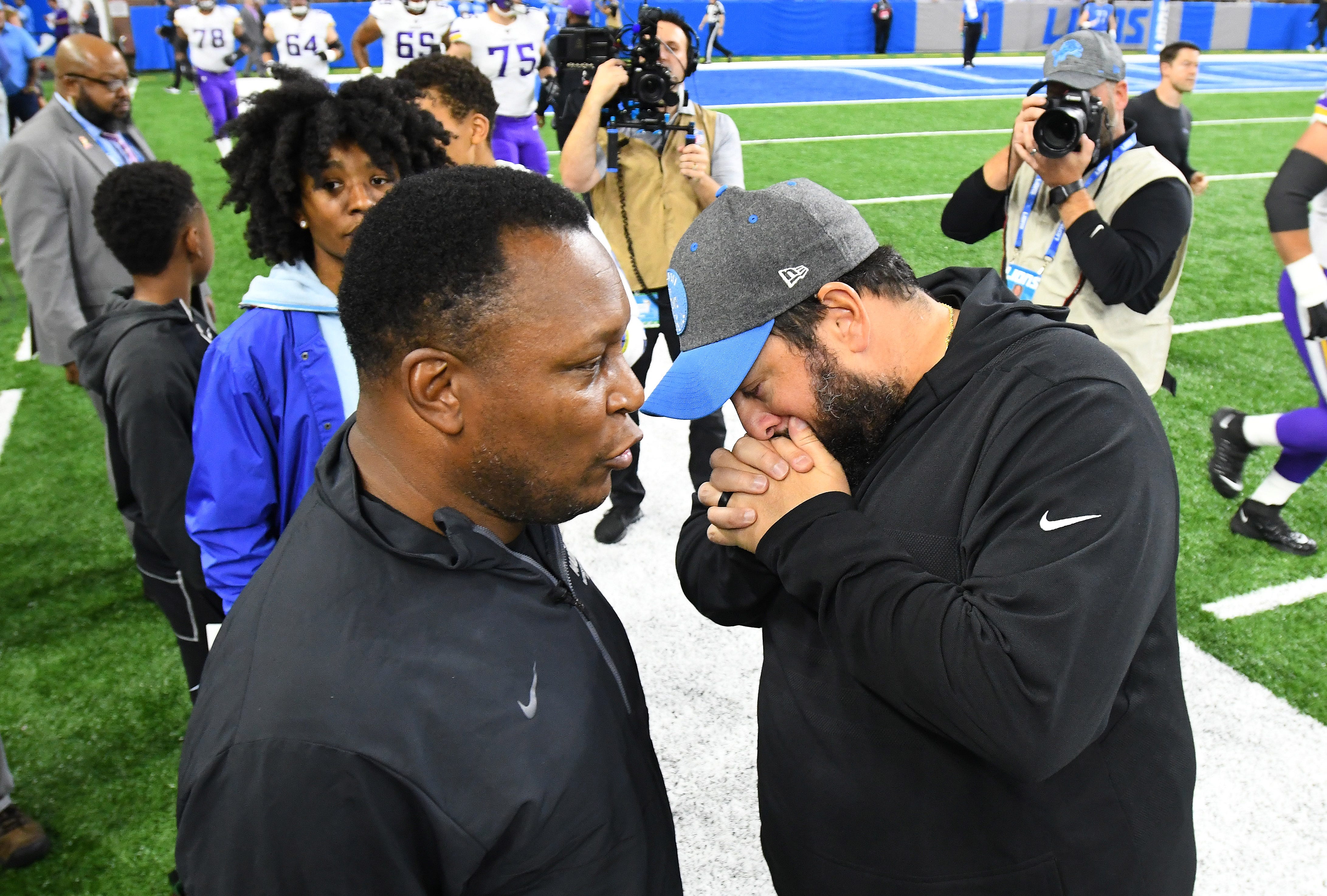 NFL Hall of Fame running back Barry Sanders and Lions head coach Matt Patricia, who covers his mouth as he talks, chat on the sidelines before the game.