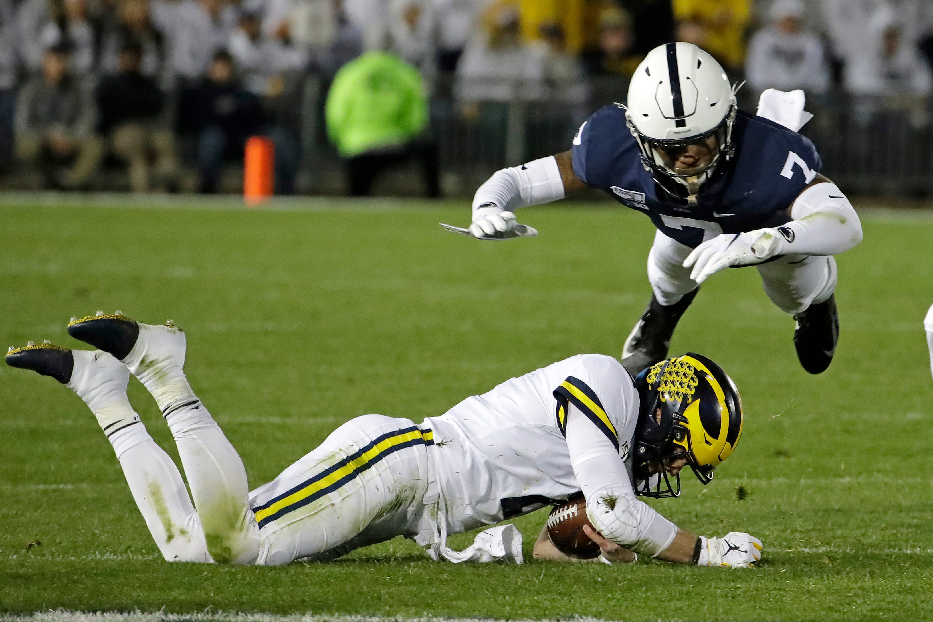 Penn State safety Jaquan Brisker (7) leaps to avoid a sliding Michigan quarterback Shea Patterson at the end of a scramble for a first down during the first half.
