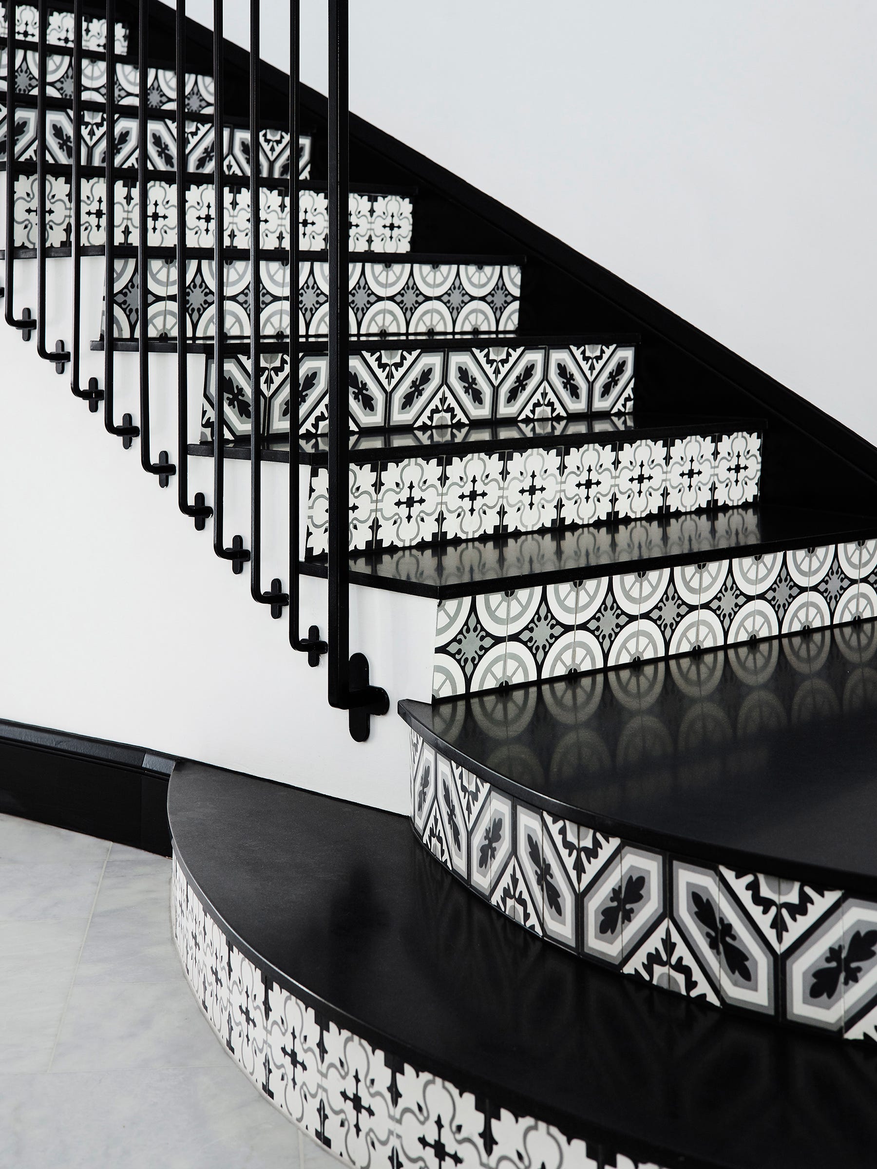 Black granite treads paired with patterned concrete tiles -- Natale's design manufactured by Teranova -- on the risers in this Spanish Revival-style decor. The client wanted a grand Hollywood-style stair. The designer says the patterns' alluring rhythm draws the eye up, and the repeated lines of the iron balustrade contribute to the drama.