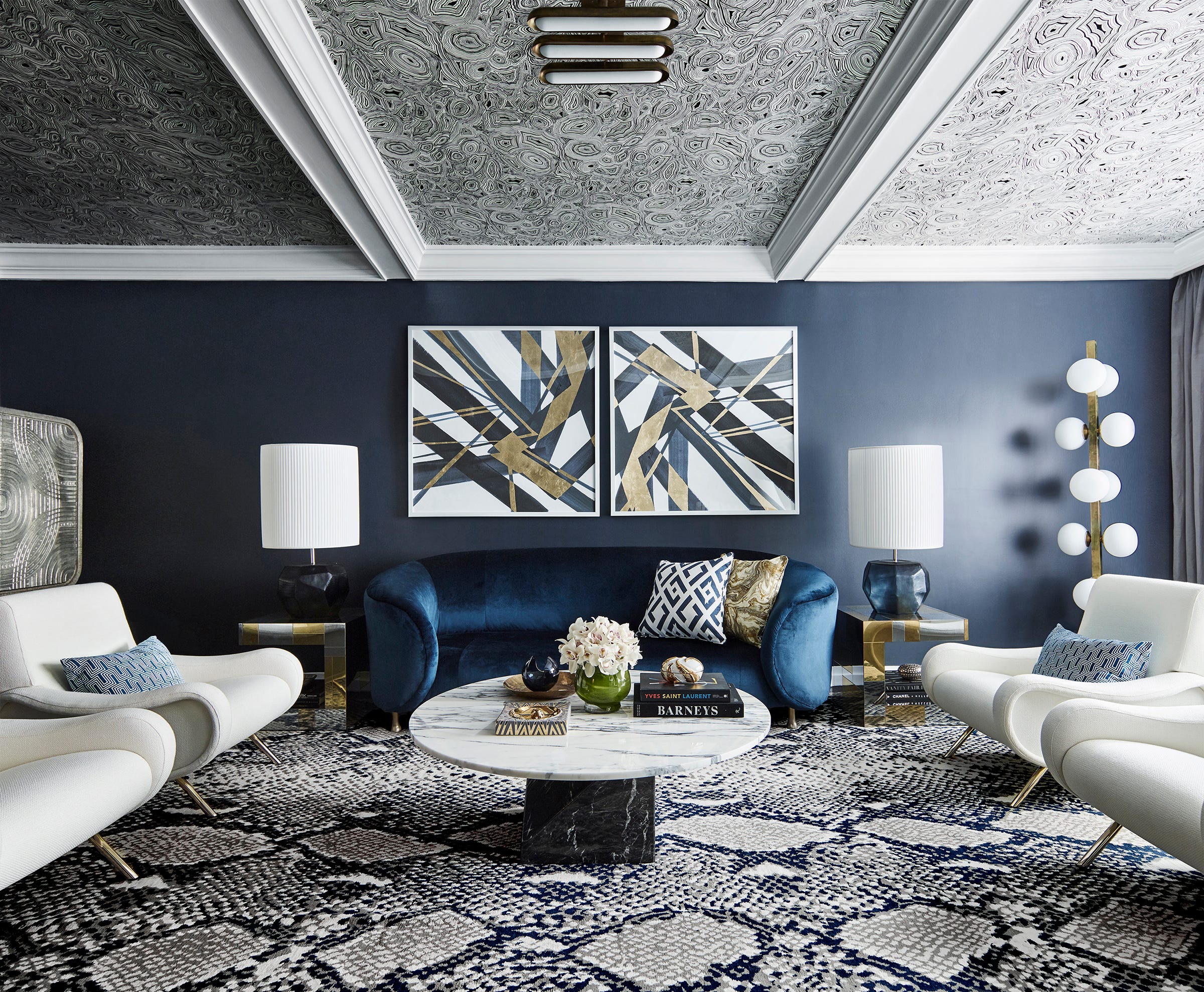 Low ceiling? Greg Natale's solution: Create a little drama. He first papered the tray ceiling in a swirling malachite pattern in black and white, painted the walls navy and furnished the space with a blue velvet sofa by Kelly Wearstler, paired with white Cassina chairs. The snakeskin rug by Diane von Furstenberg is genius. And the final touch: graphic prints with glint of gold.
