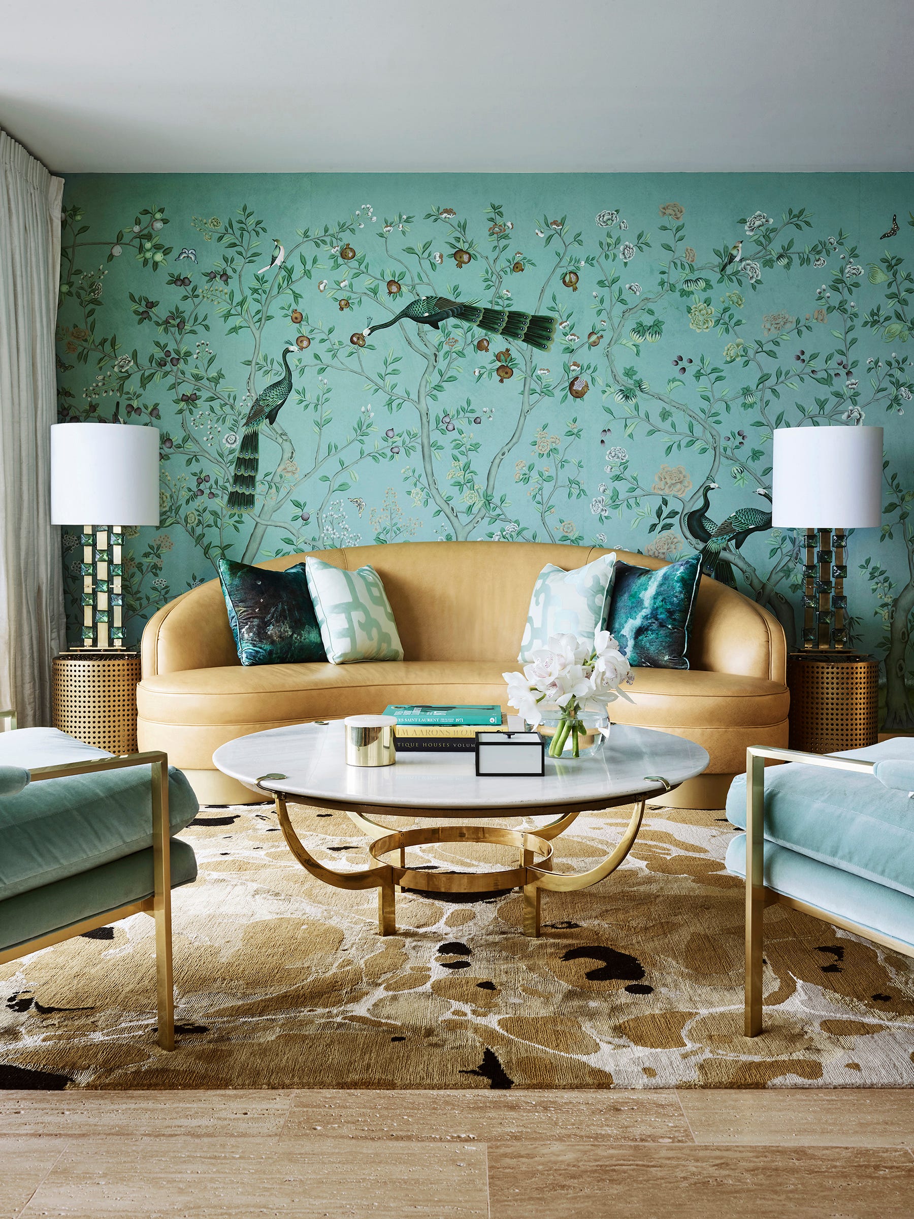 A hand-painted de Gournay wallcovering is paired with the organic Ink rug from Greg Natale's collection. The rug's warm tones carry over to the curved camel leather Dorothy Draper sofa and brass frame of the vintage coffee table, from Conley and Co., and the frame of the two chairs upholstered in velvet. This use of pattern is one of the designer's favorites, especially the vivid scene of birds that are both delicate and compelling. It's "pattern as its most extravagant," Natale says.