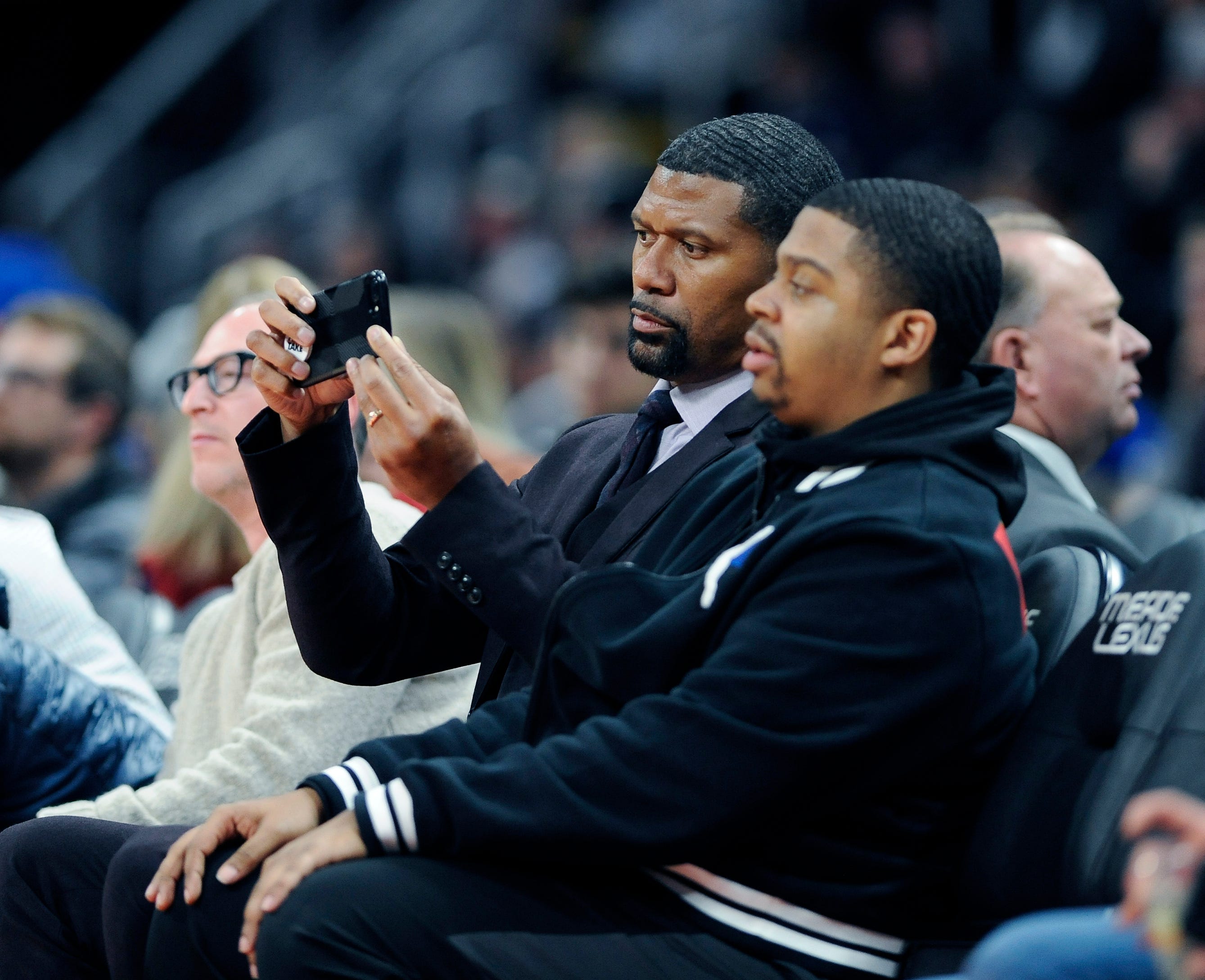Jalen Rose, right, with a phone, takes photos of the action in the second quarter.